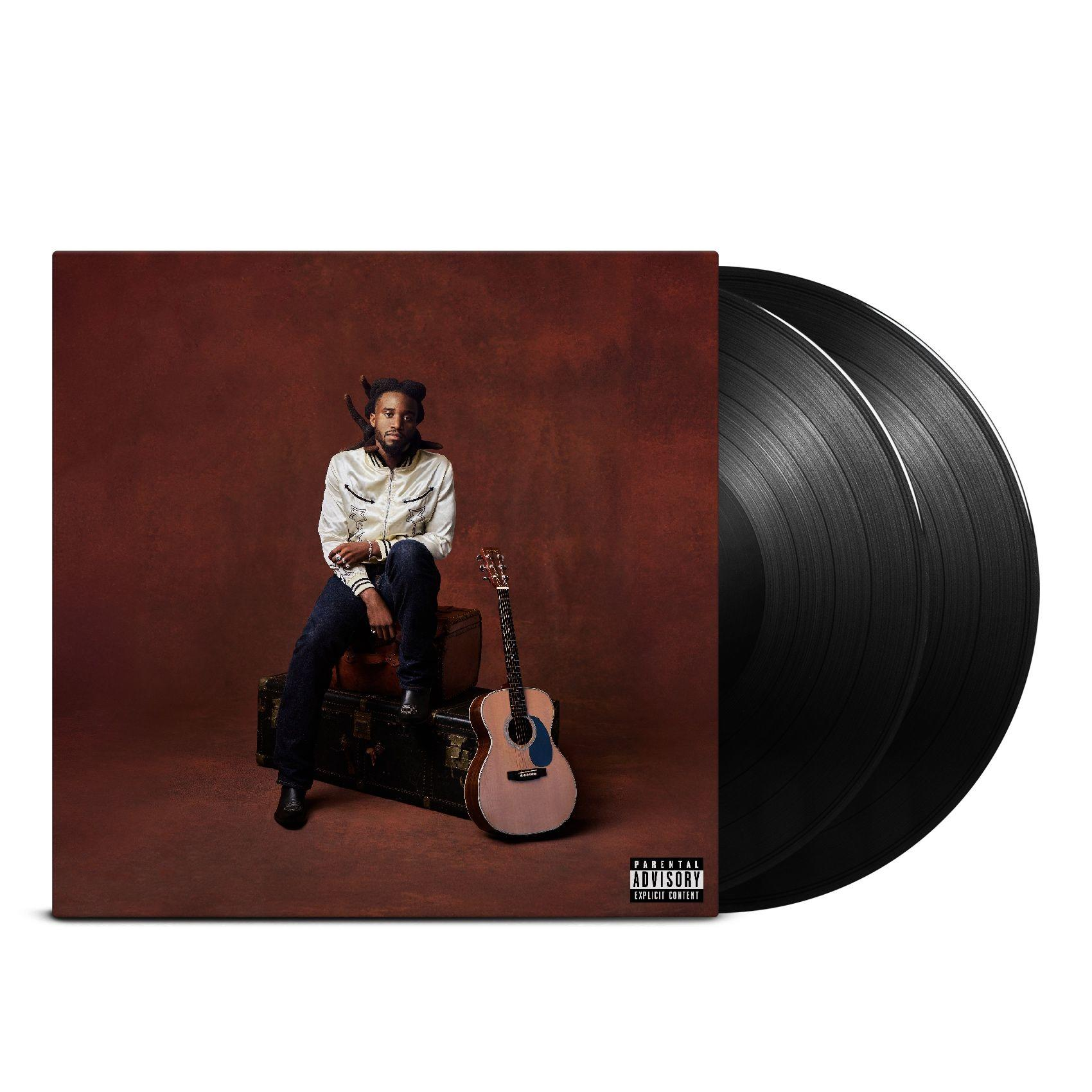 Mann sitzt auf Truhen, Gitarre daneben. Albumcover mit zwei Schallplatten. Brauner Hintergrund, weiße Jacke, schwarze Hose.