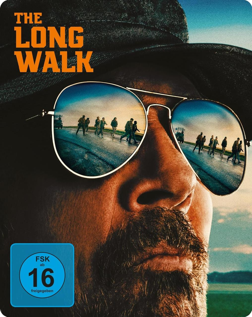 DVD-Cover von The Long Walk. Ein Mann mit Sonnenbrille spiegelt Menschen wider, die auf einer Straße gehen. FSK 16 Logo ist sichtbar.