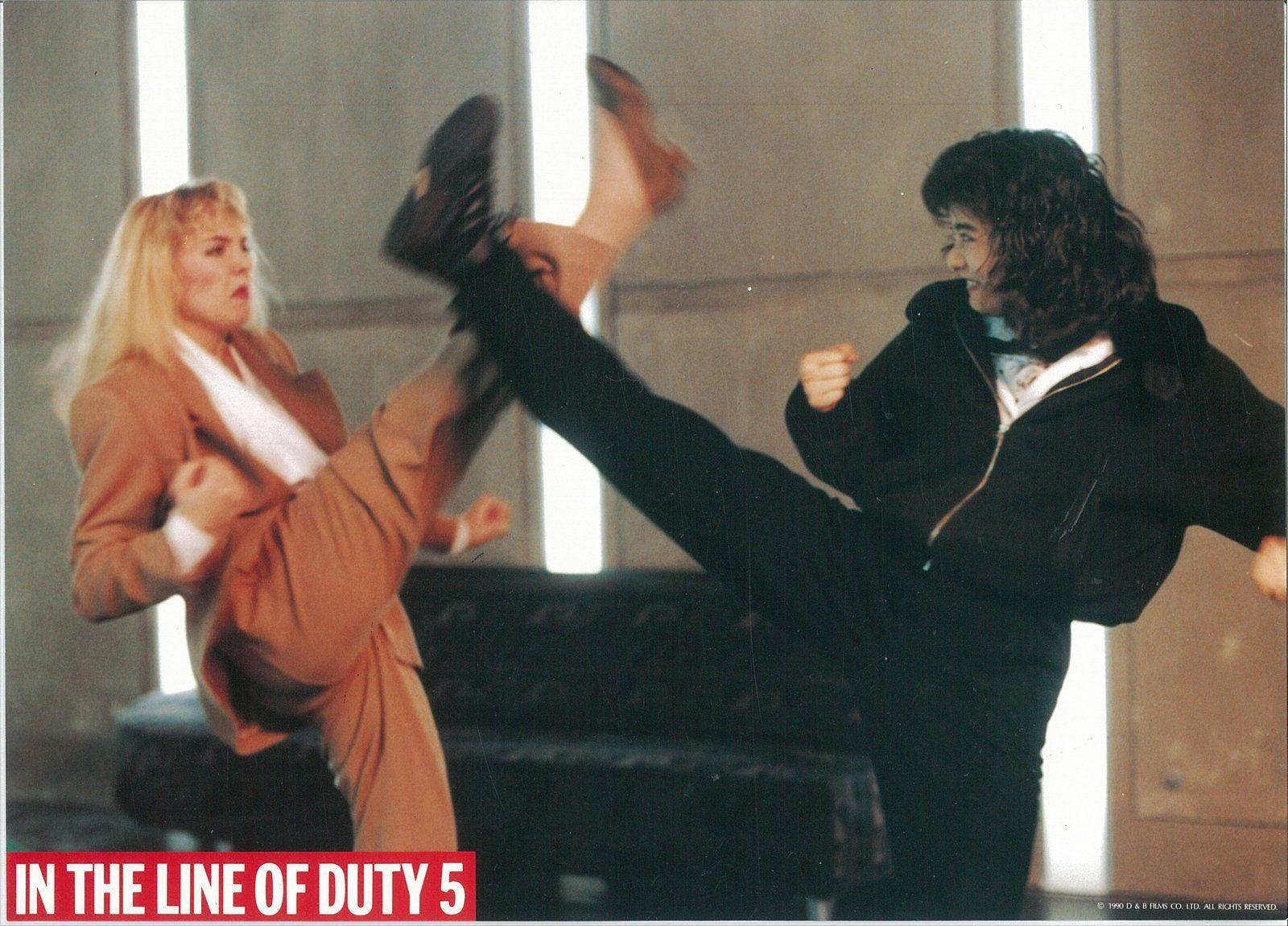 Zwei Frauen treten sich in einer Kampfszene. Eine trägt einen Anzug, die andere eine schwarze Jacke. Unten steht 'In the line of duty 5'.