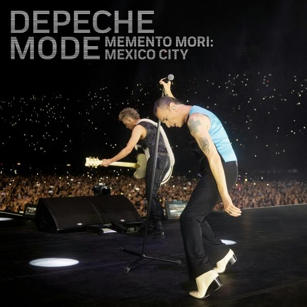 Depeche Mode-Auftritt. Ein Sänger mit Mikrofon, der andere mit Gitarre. Große Menschenmenge im Hintergrund. Bühnenlichter und Textüberlagerung.