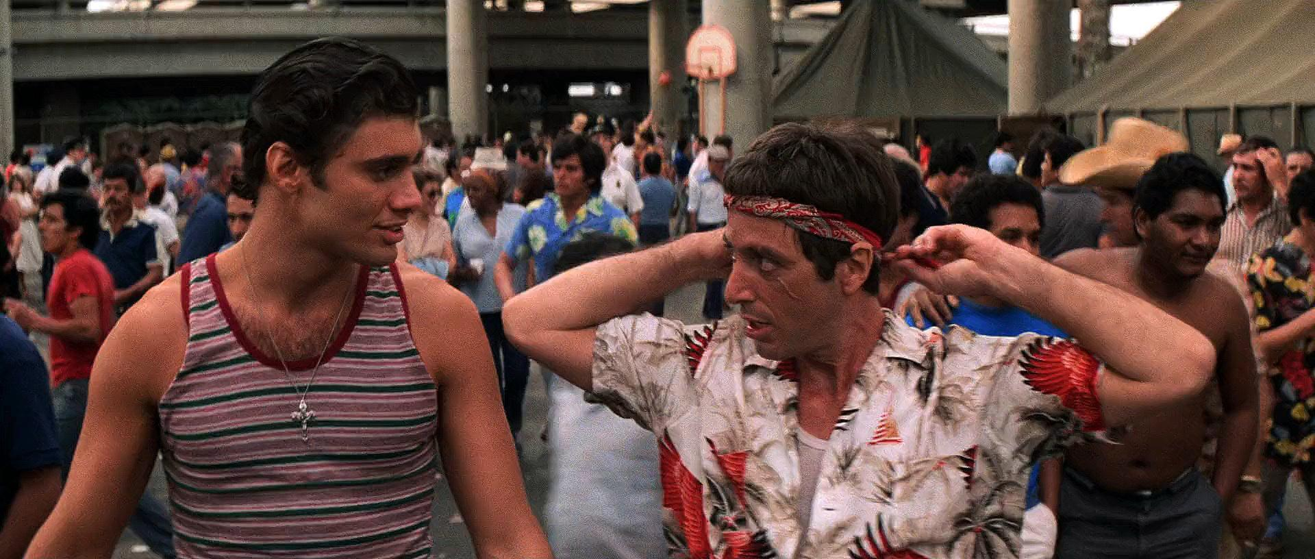 Zwei Männer in einer Menschenmenge. Einer in einem gestreiften Tanktop, der andere in einem Blumenhemd, bindet ein Stirnband.
