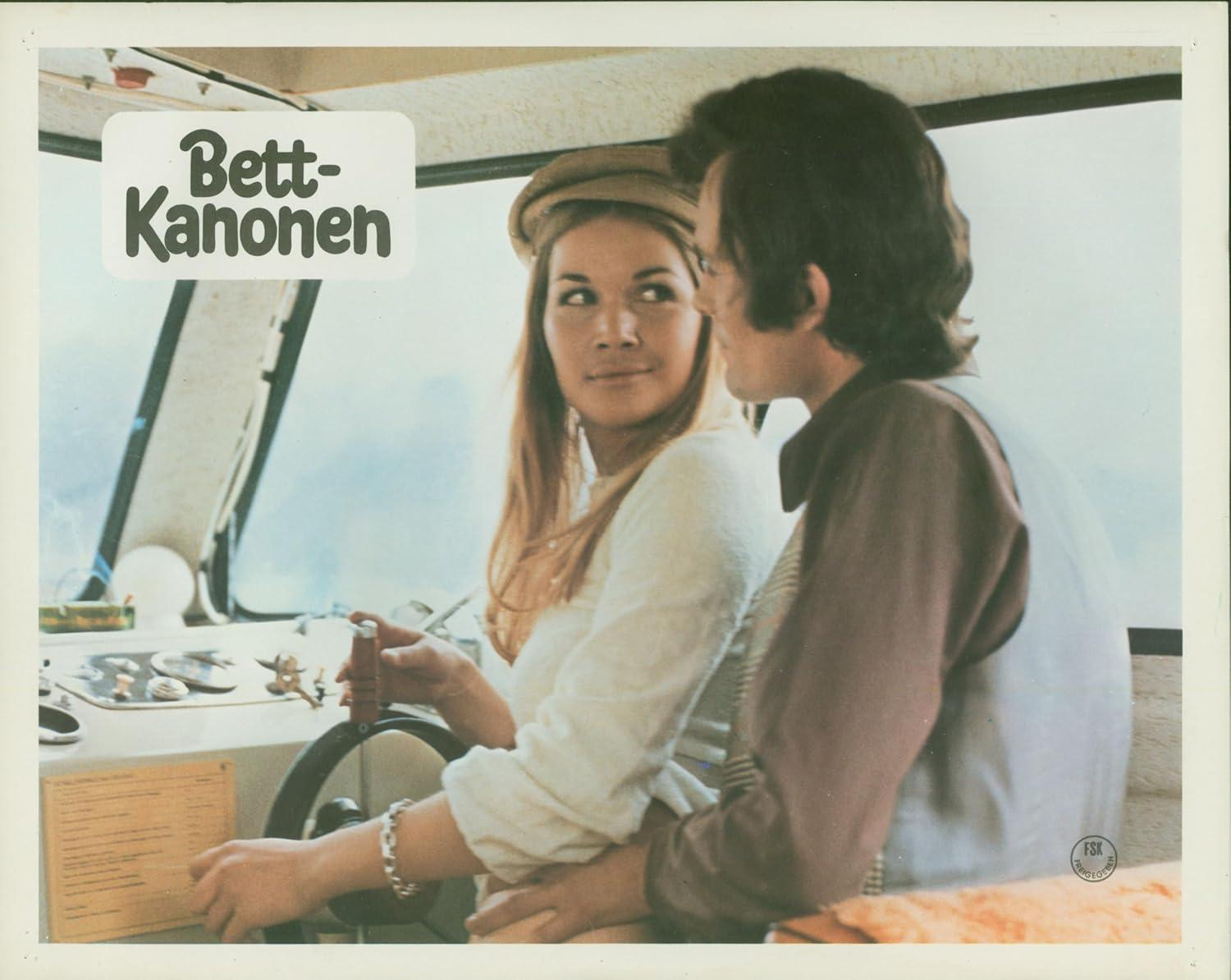 Eine Frau steuert ein Boot. Ein Mann ist neben ihr. Der Bootsname ist auf Deutsch. Die Frau trägt ein weißes Hemd und der Mann ein braunes Hemd.