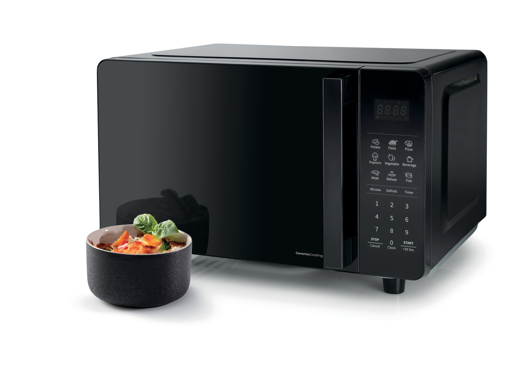 Schwarze Mikrowelle mit Digitalanzeige. Eine Schüssel mit Essen und Basilikum steht davor. Weißer Hintergrund.