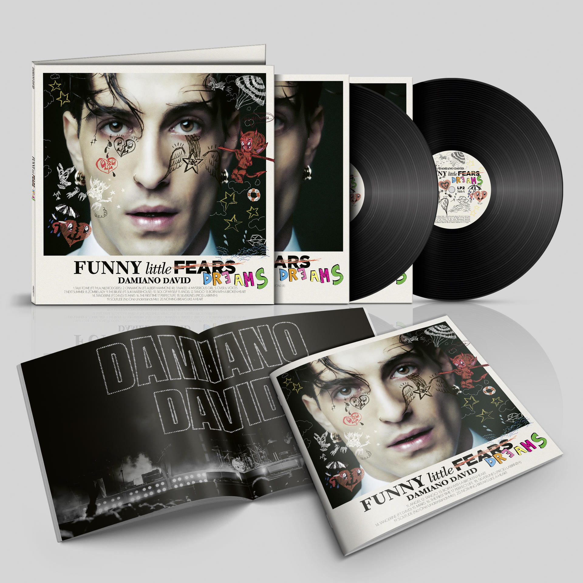 Albumcover mit Damiano Davids Gesicht, Tätowierungen und Albumtitel. Vinylplatten sind sichtbar. Ein Heft ist geöffnet.