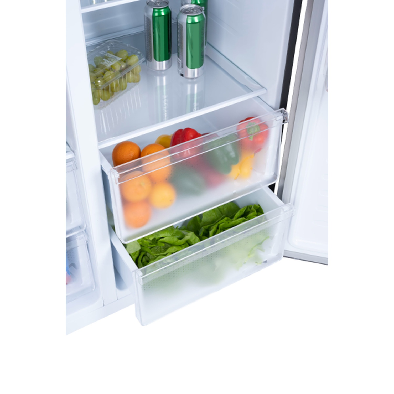 Inside a fridge: oranges, peppers, lettuce, and grapes in drawers. Canned drinks are on the top shelf.