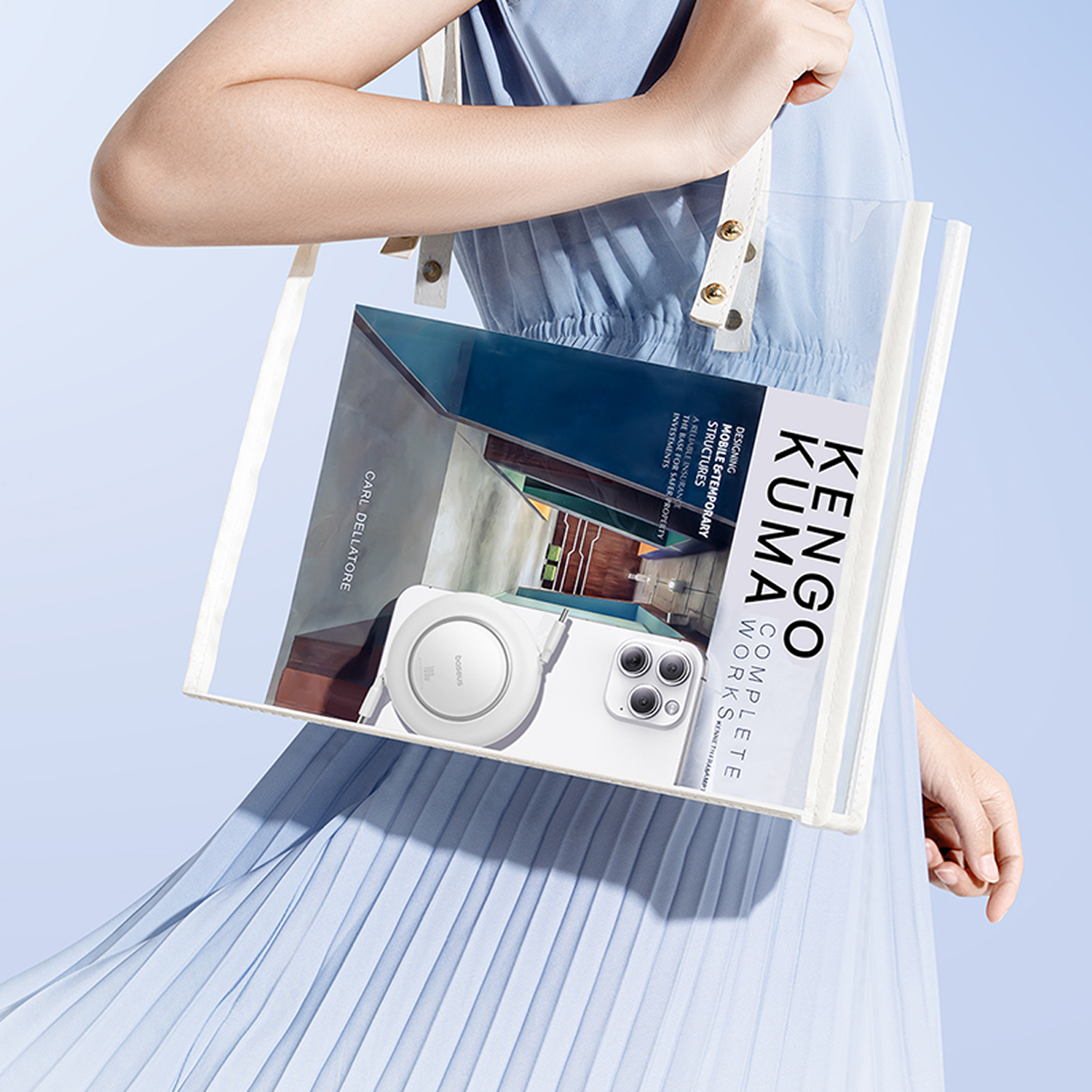 Una persona sostiene una bolsa transparente con un libro y un teléfono dentro. La bolsa tiene correas blancas y la persona usa un vestido azul.