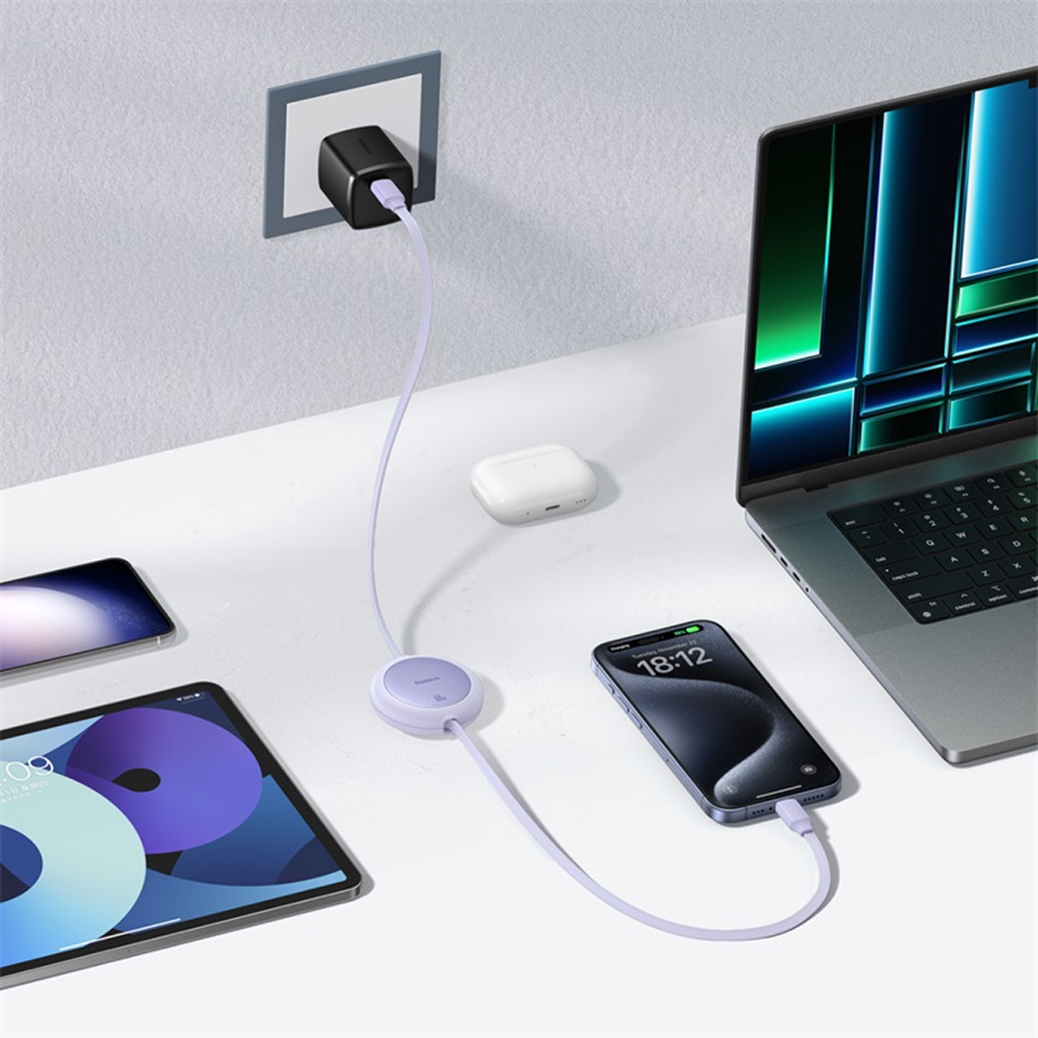 Dispositivos cargando: Portátil, teléfono y tableta. Cargador en la pared. Estuche de AirPods. Mesa blanca.