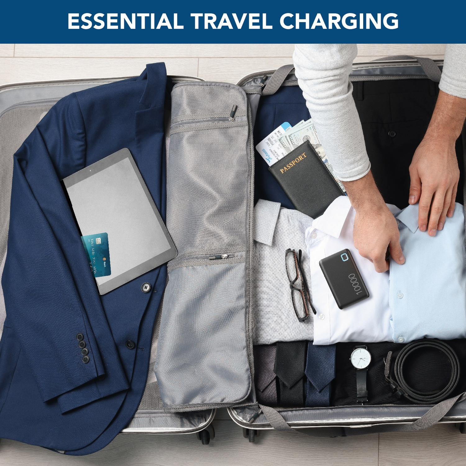 Valigia aperta con vestiti, tablet, passaporto, soldi, occhiali, orologio, cravatta, cintura e power bank. Una persona sta facendo la valigia.
