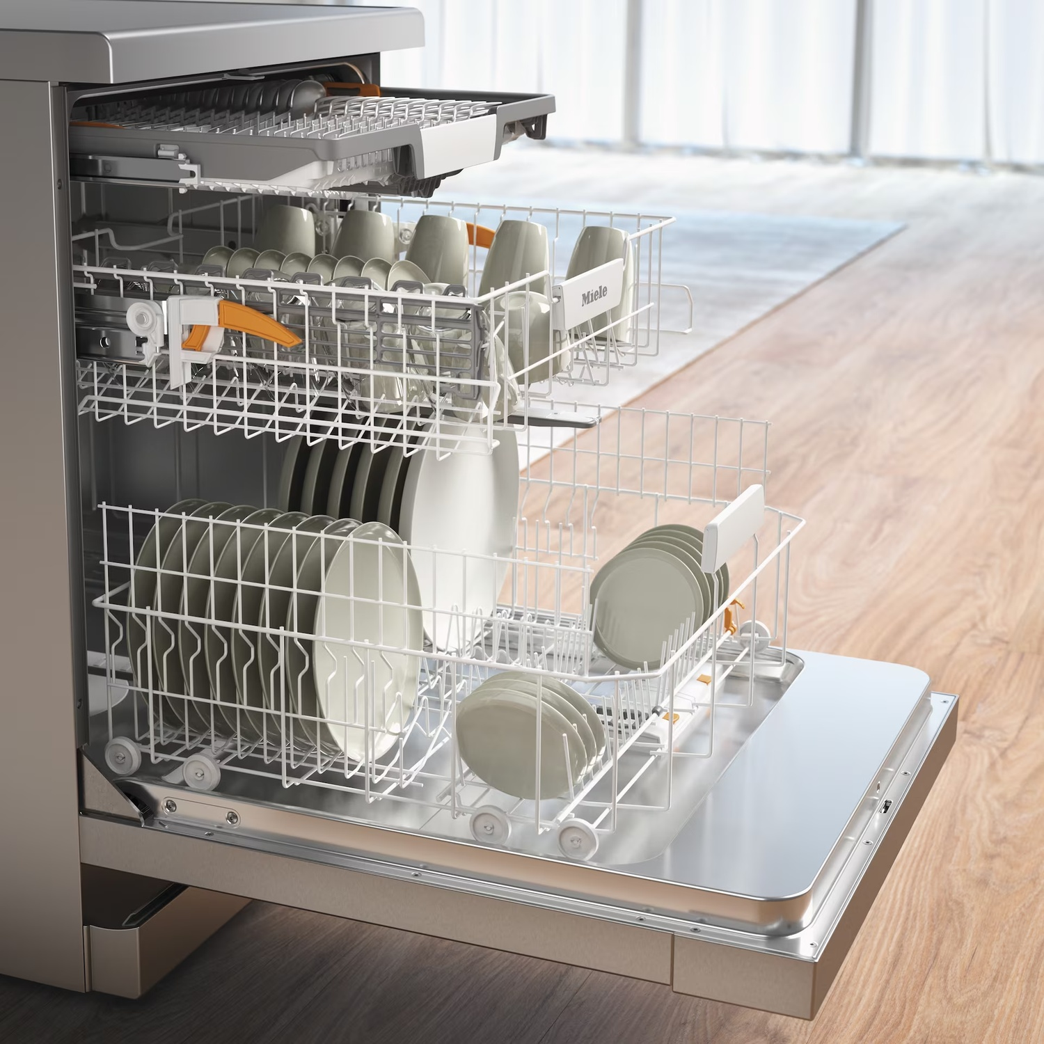 Open dishwasher with dishes inside. Plates and cups are visible. The dishwasher is stainless steel, and the floor is wooden.