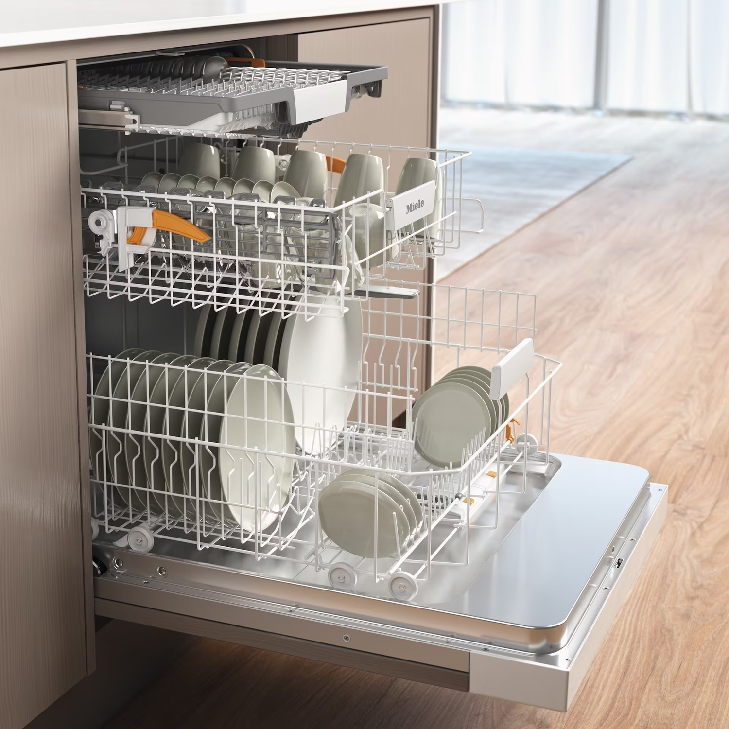 Open dishwasher with dishes and cups inside. Wooden floor visible. Miele logo on a rack.