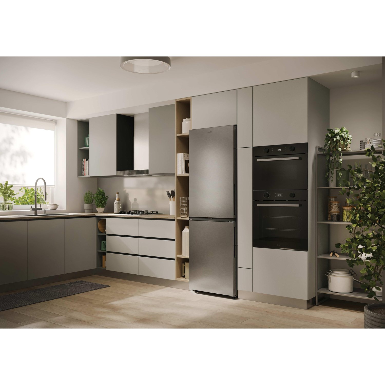Una cucina moderna con mobili grigi, elettrodomestici in acciaio inossidabile e pavimenti in legno. Una grande pianta a destra.