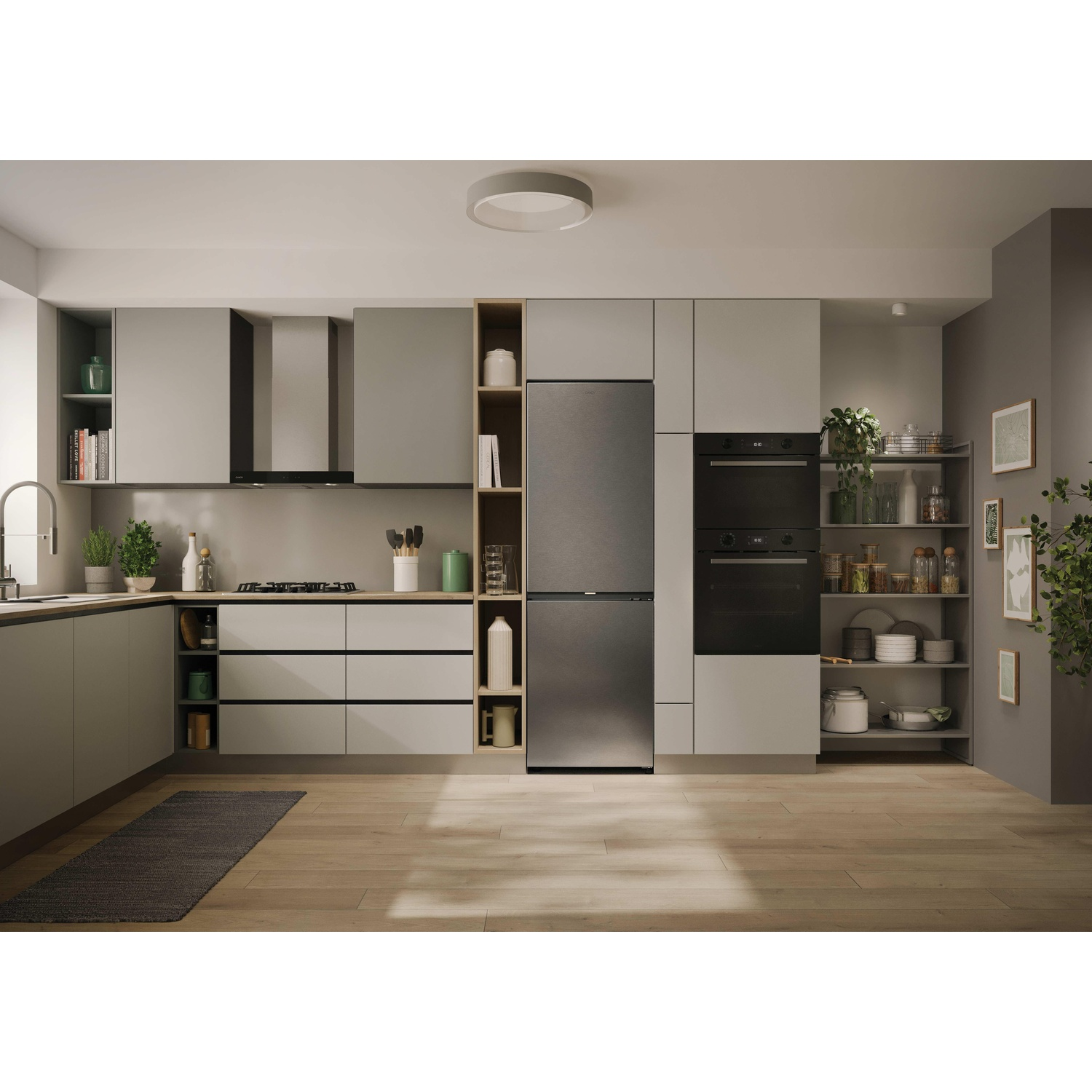 Una cucina moderna con mobili grigi, elettrodomestici, pavimento in legno e tappeto. Presenti anche piante e oggetti decorativi.