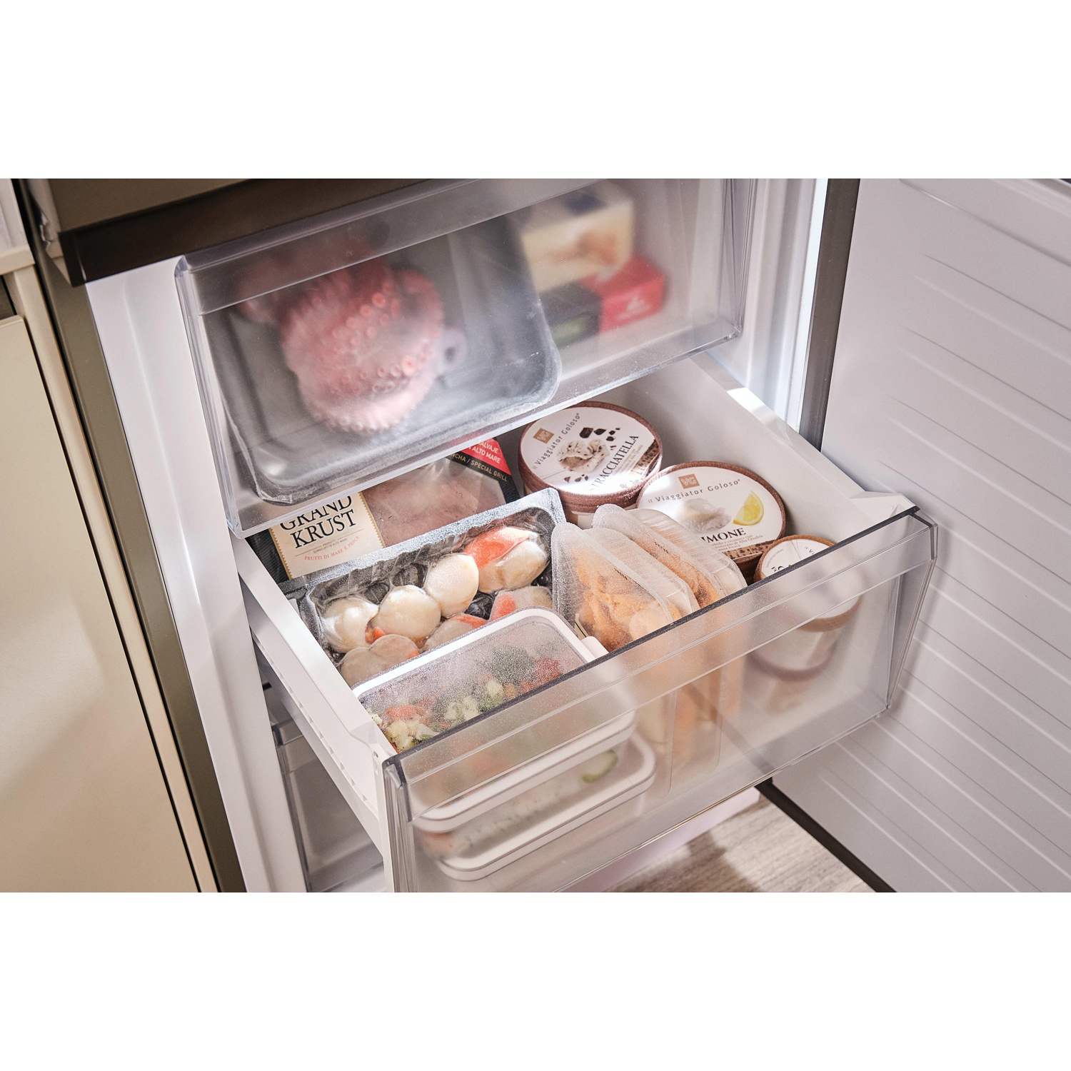 Frigorifero aperto con pesce confezionato, gelato e altri alimenti surgelati. Il cassetto superiore ha il polpo, il cassetto centrale ha le capesante.