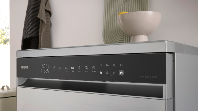 Panel sterowania zmywarki z wyświetlaczem ustawień. Miska z cytrynami powyżej. Ręcznik wisi na ścianie.