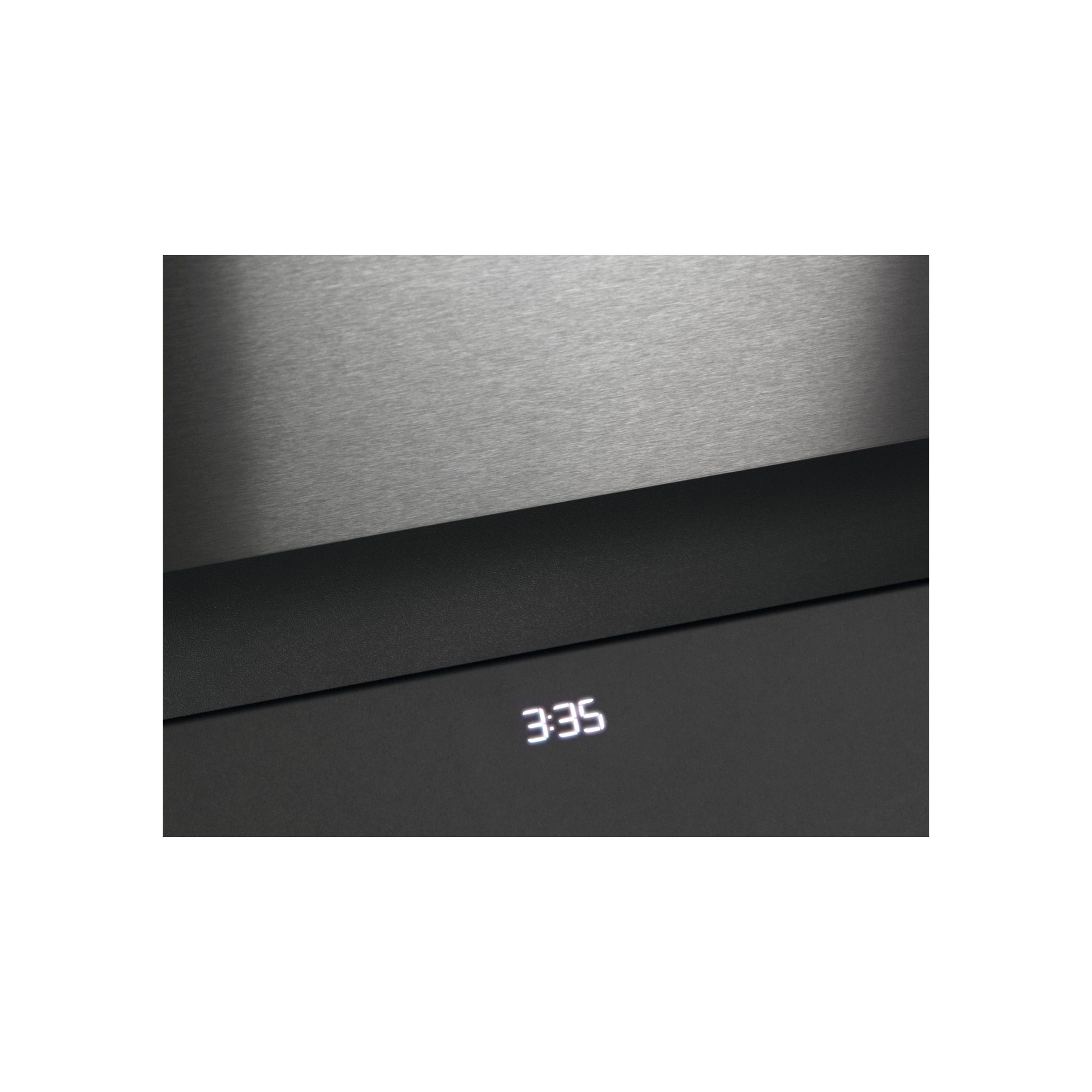 Zbliżenie ciemnego urządzenia z wyświetlaczem "3:35". Tło to szczotkowany metal.