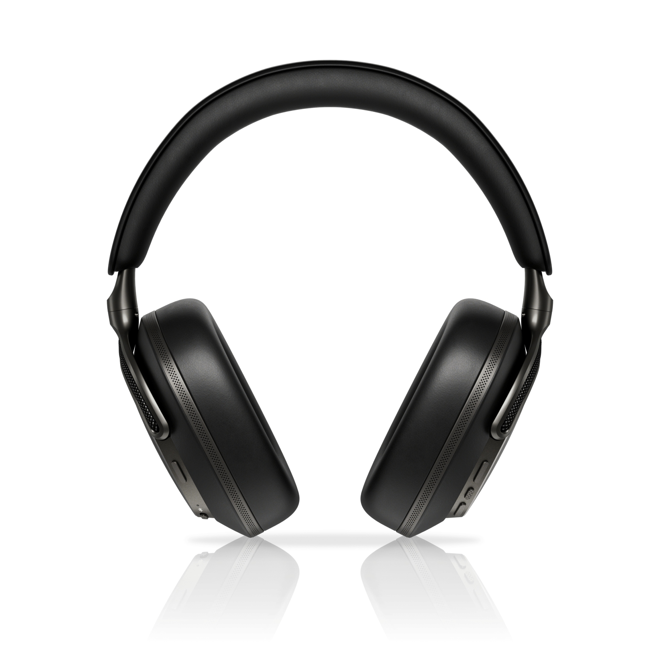 Auriculares negros sobre fondo blanco, con superficie reflectante. Detalles de los auriculares y la diadema son visibles.