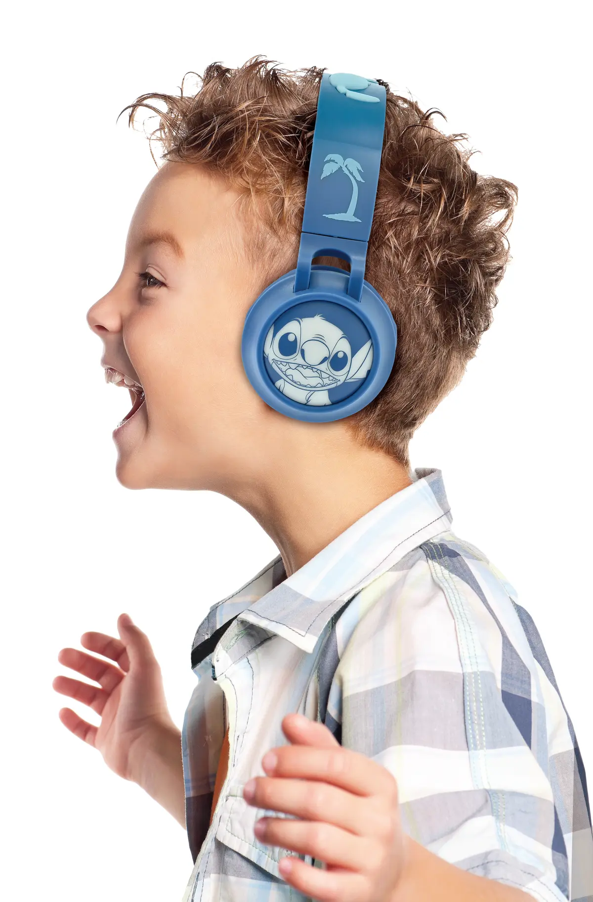 Un niño con auriculares Stitch azules sonríe. Su camisa es a cuadros y gesticula con las manos.