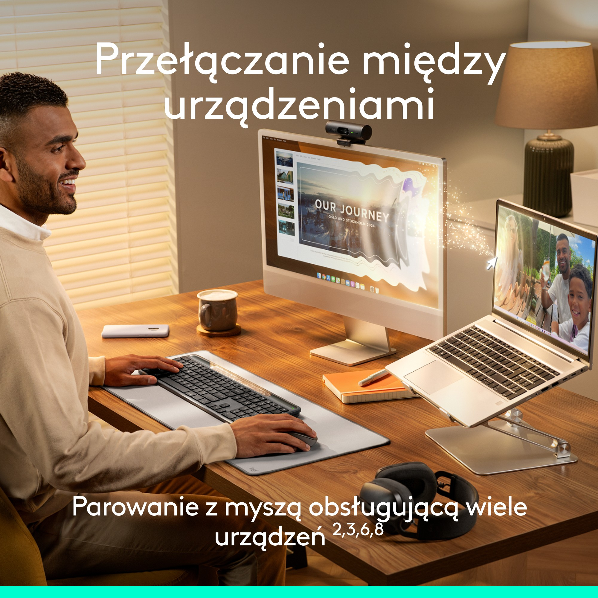 Mężczyzna przy biurku używa klawiatury, podłączonej do monitora i laptopa. Zdjęcie rodzinne na ekranie laptopa. Słuchawki i mysz są widoczne.
