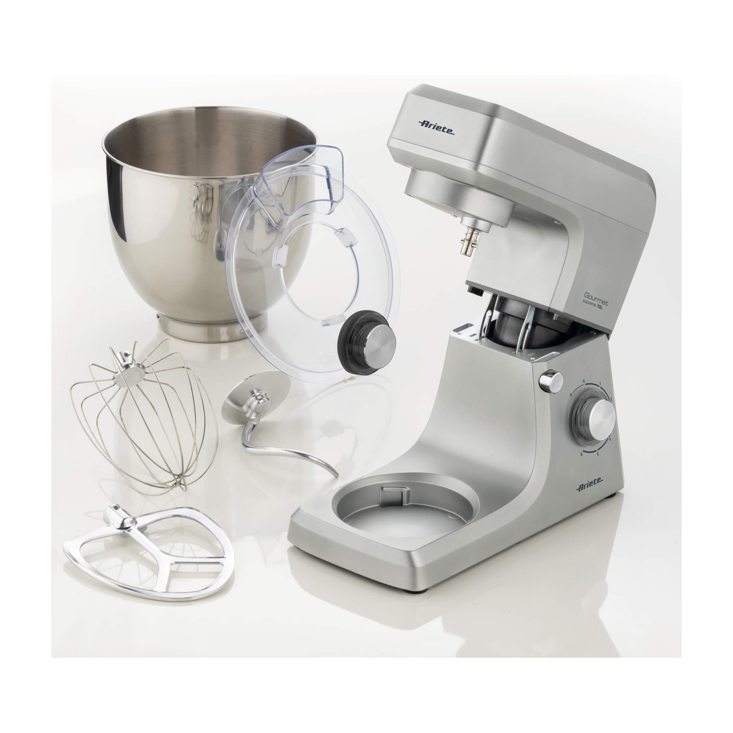 Un mixer da supporto argento con accessori: frusta, gancio impastatore e battitore, insieme a una ciotola e un paraspruzzi.