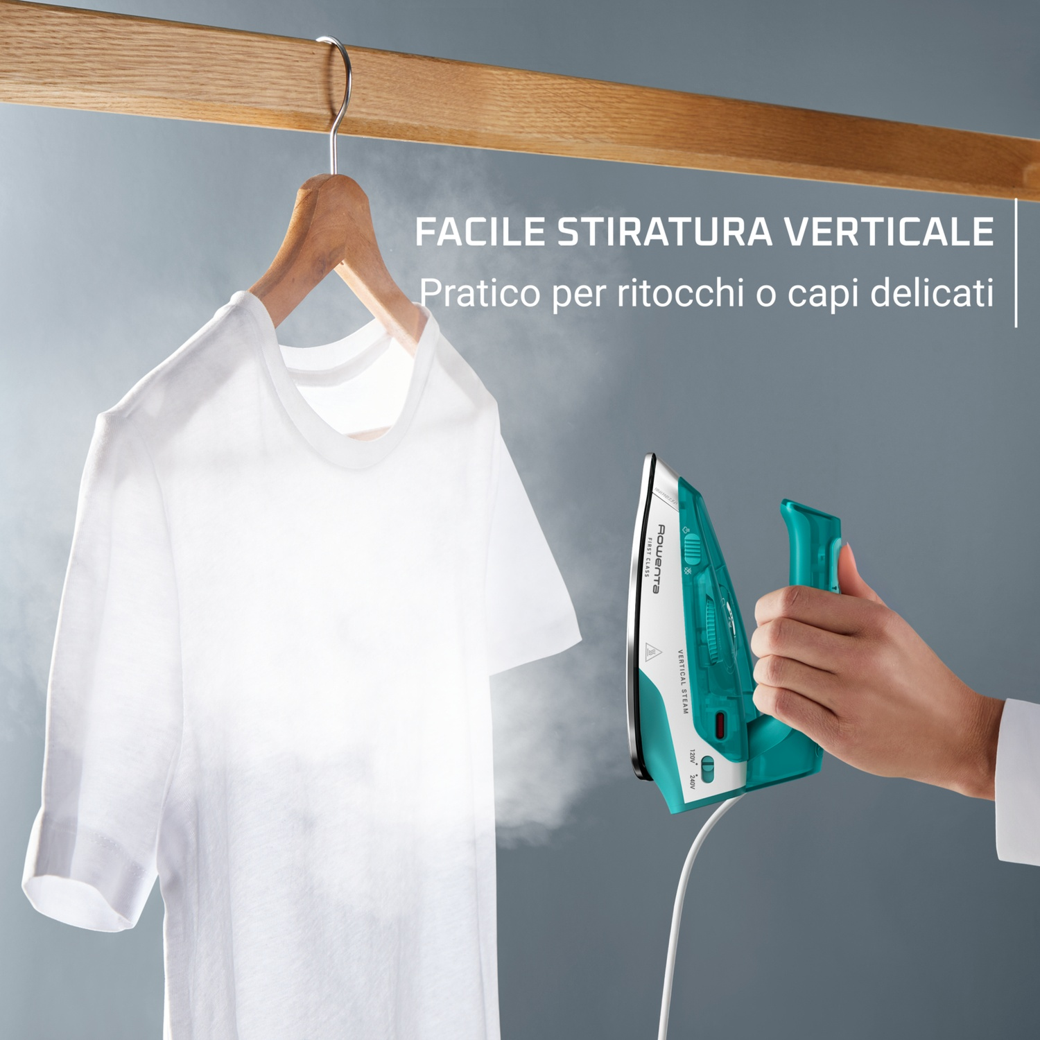 Una maglietta bianca è appesa a una gruccia di legno. Un ferro da stiro turchese e bianco è tenuto da una mano, che vaporizza la camicia.