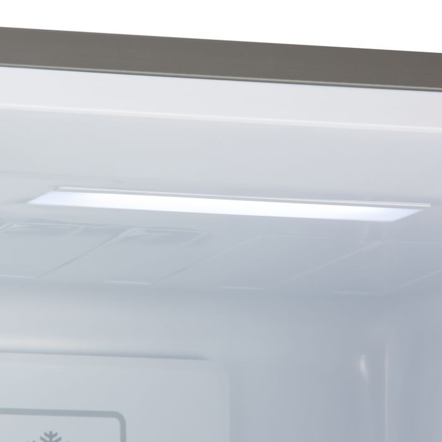 À l'intérieur d'un réfrigérateur. Une lumière rectangulaire vive illumine la partie supérieure. L'intérieur est blanc, le haut a une garniture grise.