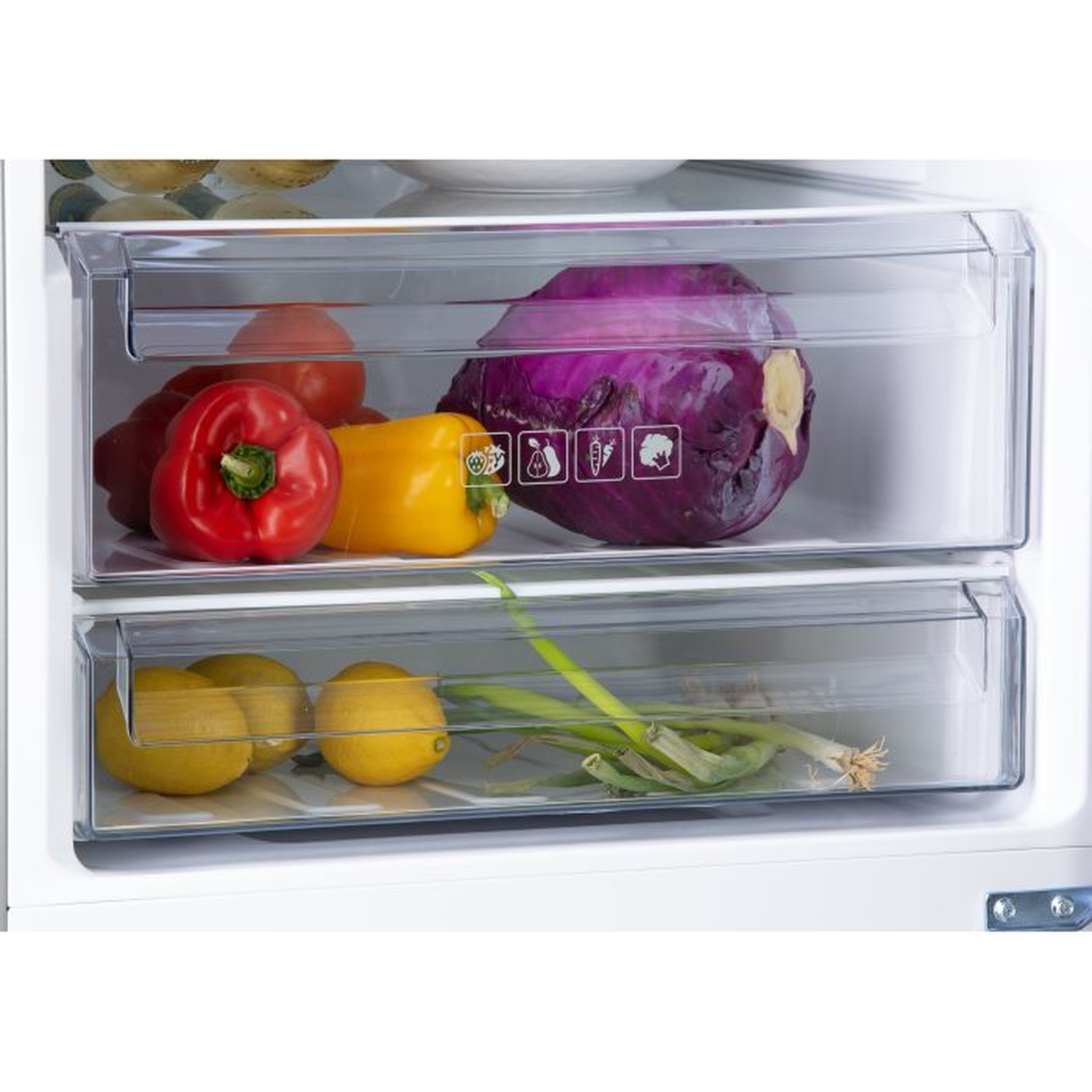 À l'intérieur d'un réfrigérateur, deux tiroirs contiennent des légumes. Poivrons, tomates et un chou sont au-dessus. Citrons et oignons verts en bas.