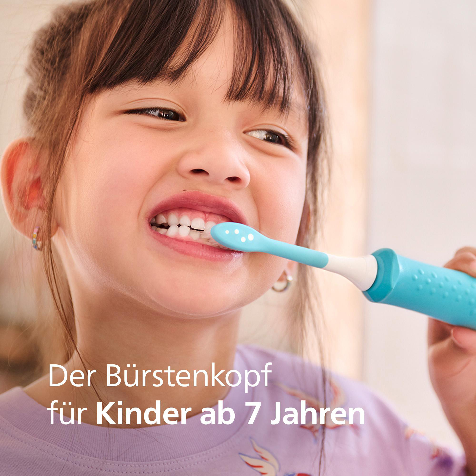 Ein Mädchen putzt sich mit einer blauen Zahnbürste die Zähne. Sie lächelt und zeigt ihre Zähne. Text: 'Der Bürstenkopf für Kinder ab 7 Jahren'.