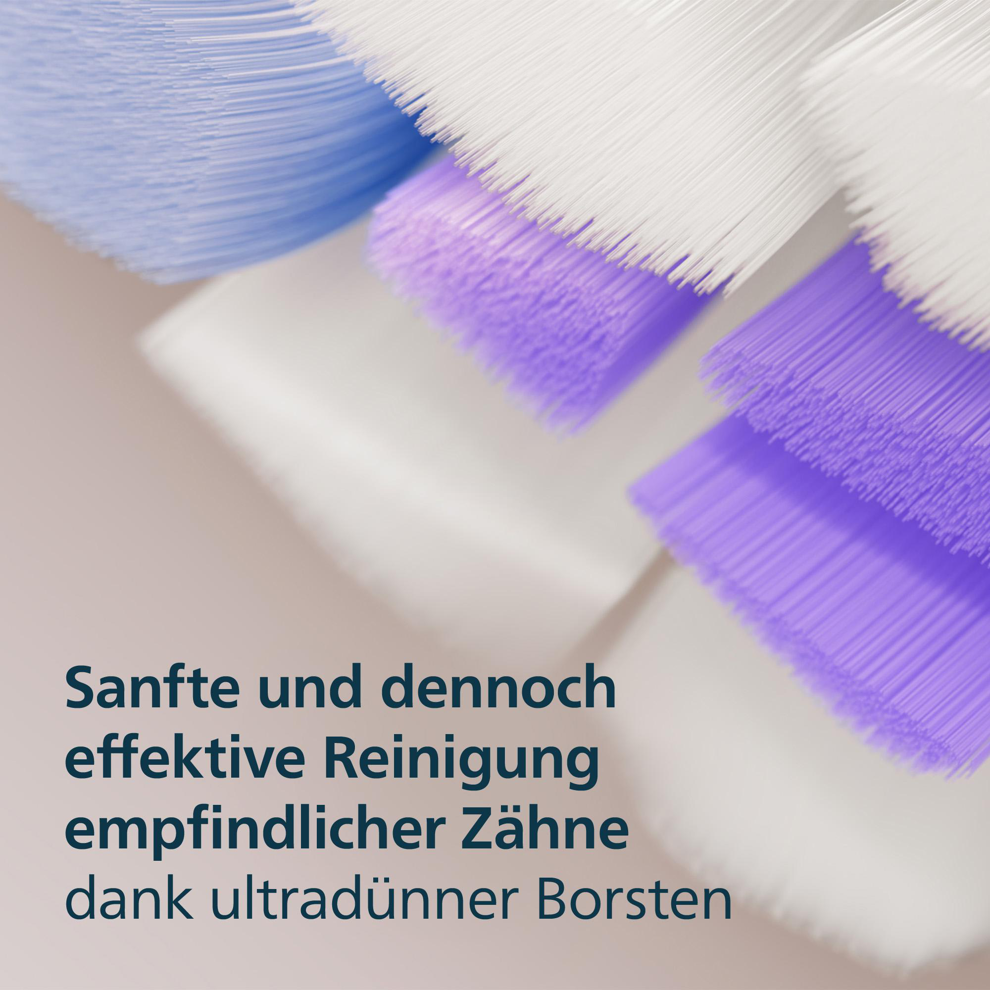 Nahaufnahme von Zahnbürstenborsten: lila, weiß und blau. Text unten beschreibt sanfte und effektive Reinigung.