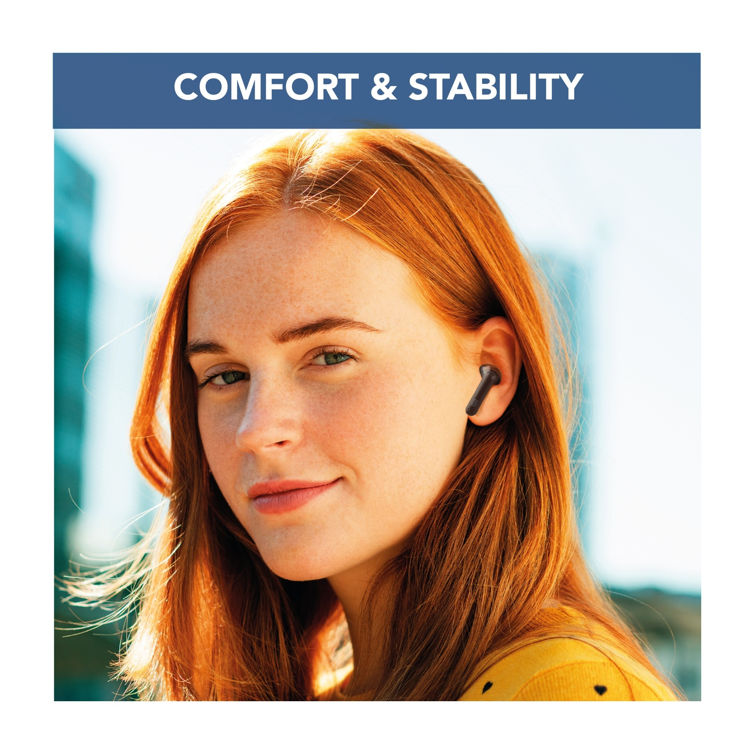 Una donna con i capelli rossi e le lentiggini indossa un auricolare nero. Il testo 'COMFORT & STABILITY' è nella parte superiore dell'immagine.