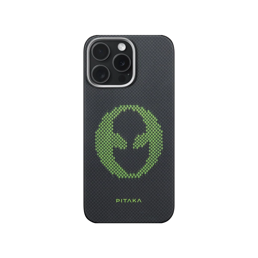 Egy iPhone szénszálas tokkal, zöld pixeles alienfej-mintával és a PITAKA szóval alul.
