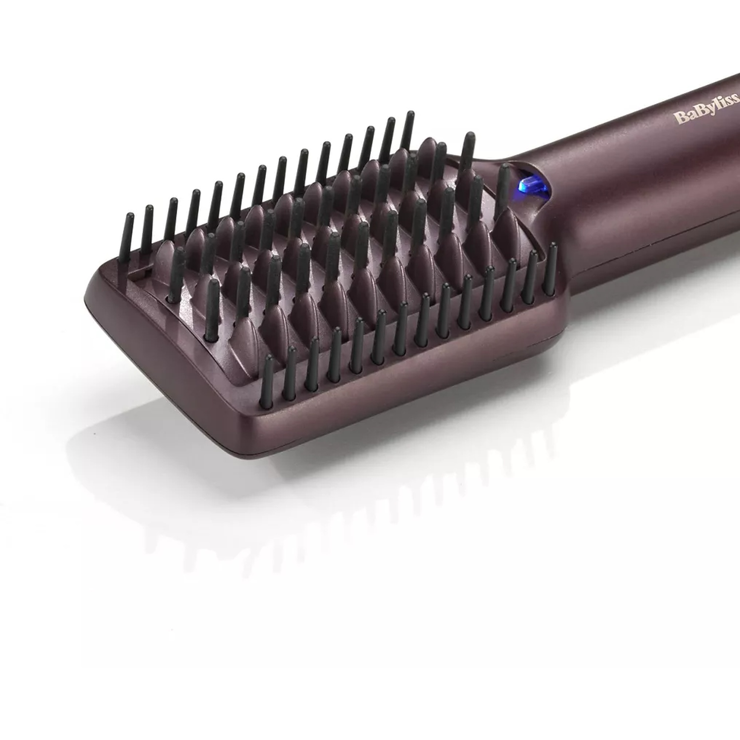 A maroon BaByliss hair straightening brush. It has black bristles and a blue power indicator. The brush is on a white surface.