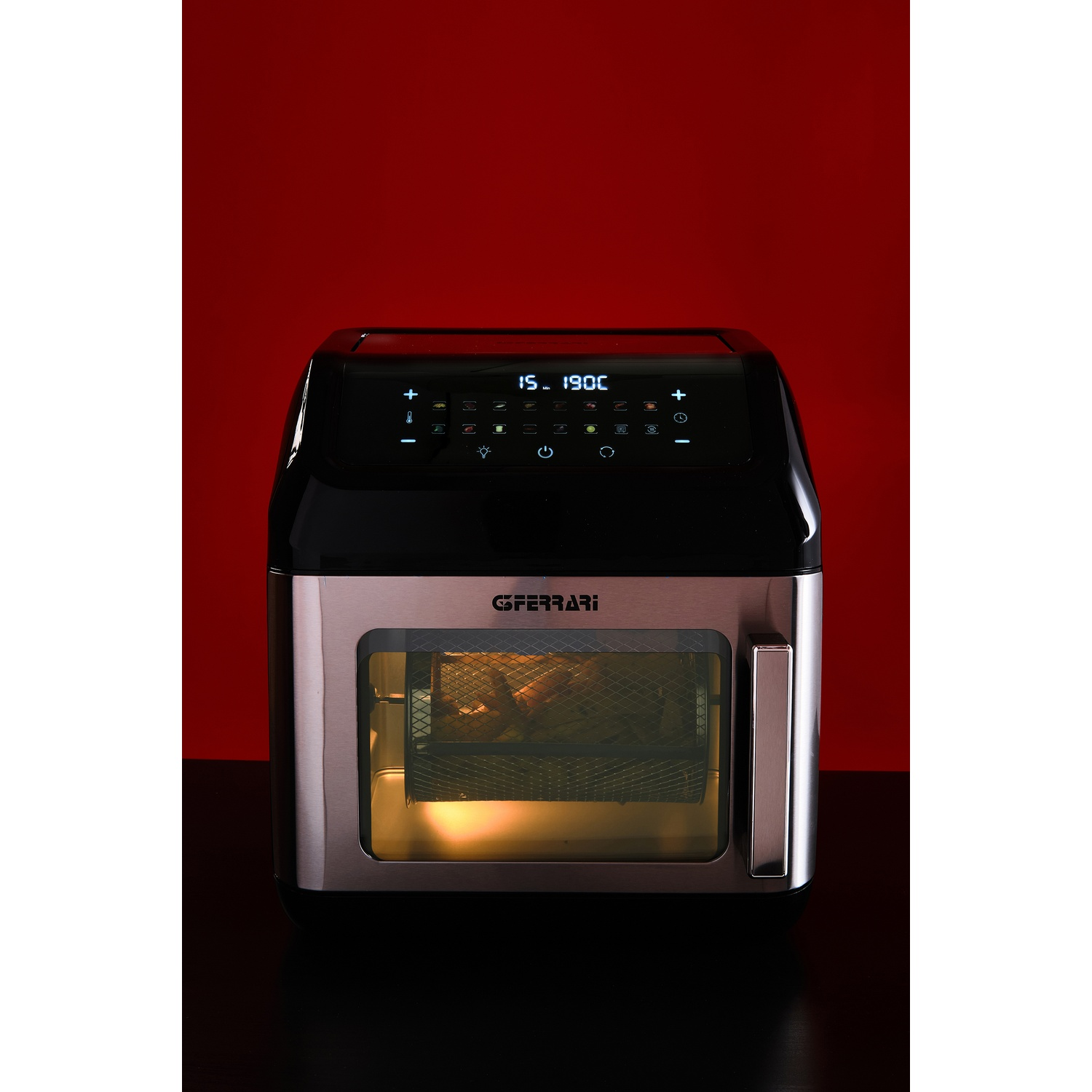 Una friggitrice ad aria con display digitale mostra 15 minuti e 190°C. È su una superficie nera contro uno sfondo rosso.