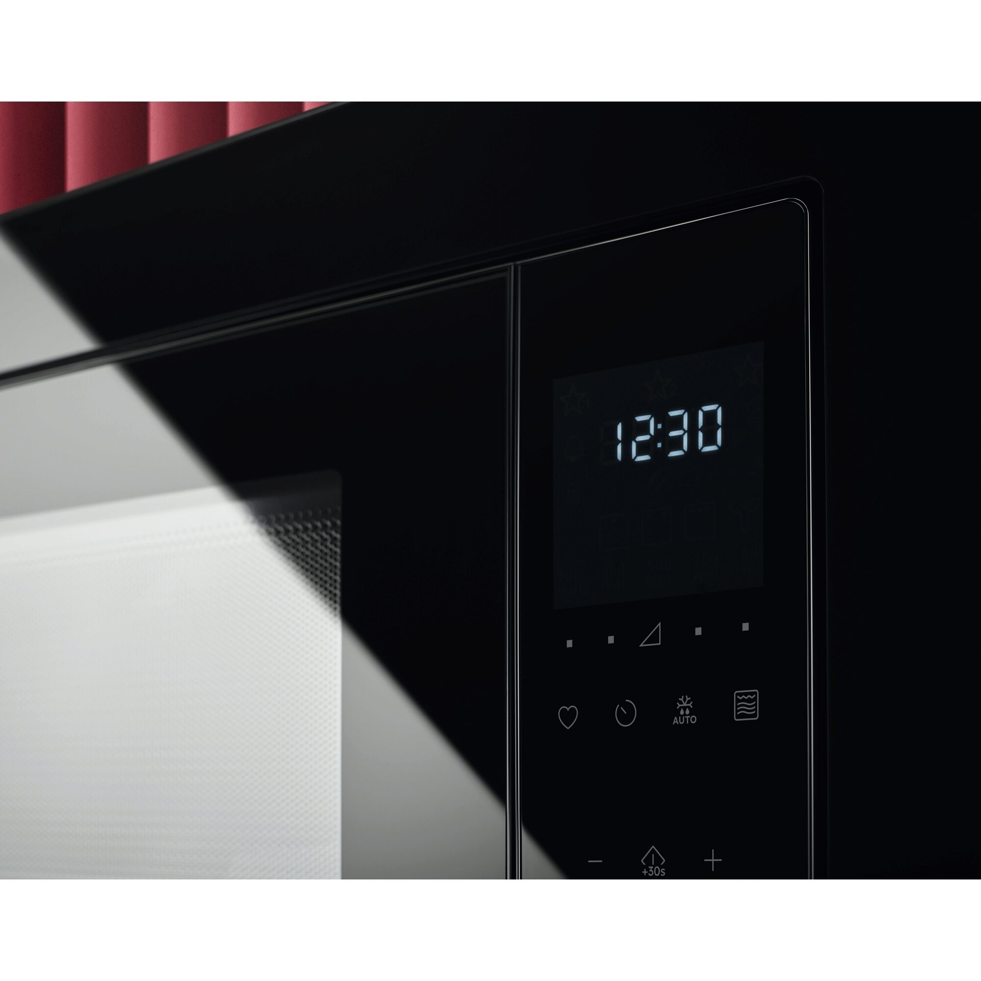 Primer plano de un microondas. Se muestra la hora 12:30. Hay botones para varias configuraciones en el panel negro.