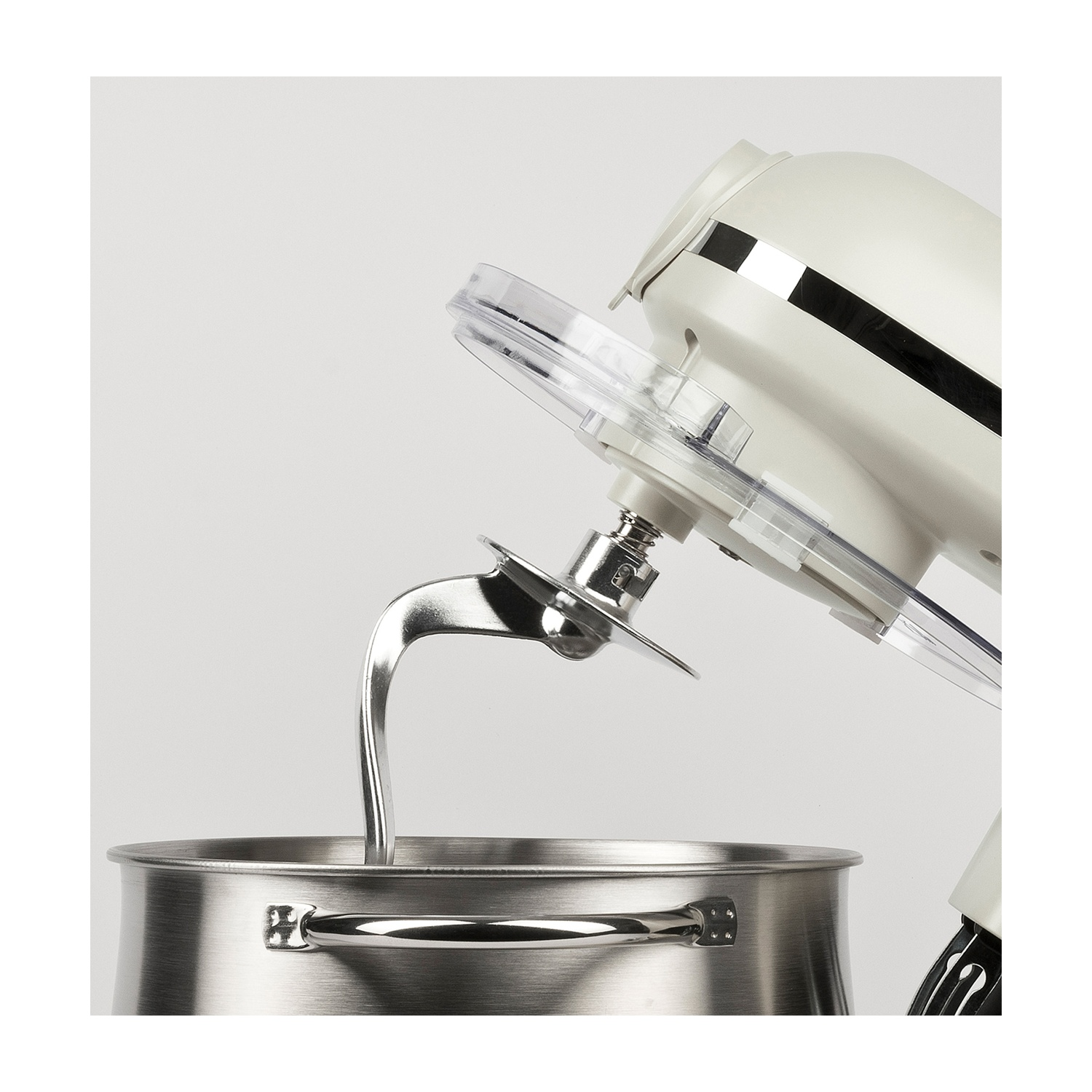 Un mixer da cucina bianco con una ciotola in acciaio inossidabile. Il braccio del mixer è abbassato nella ciotola, pronto per mescolare. Coperchio protettivo trasparente.