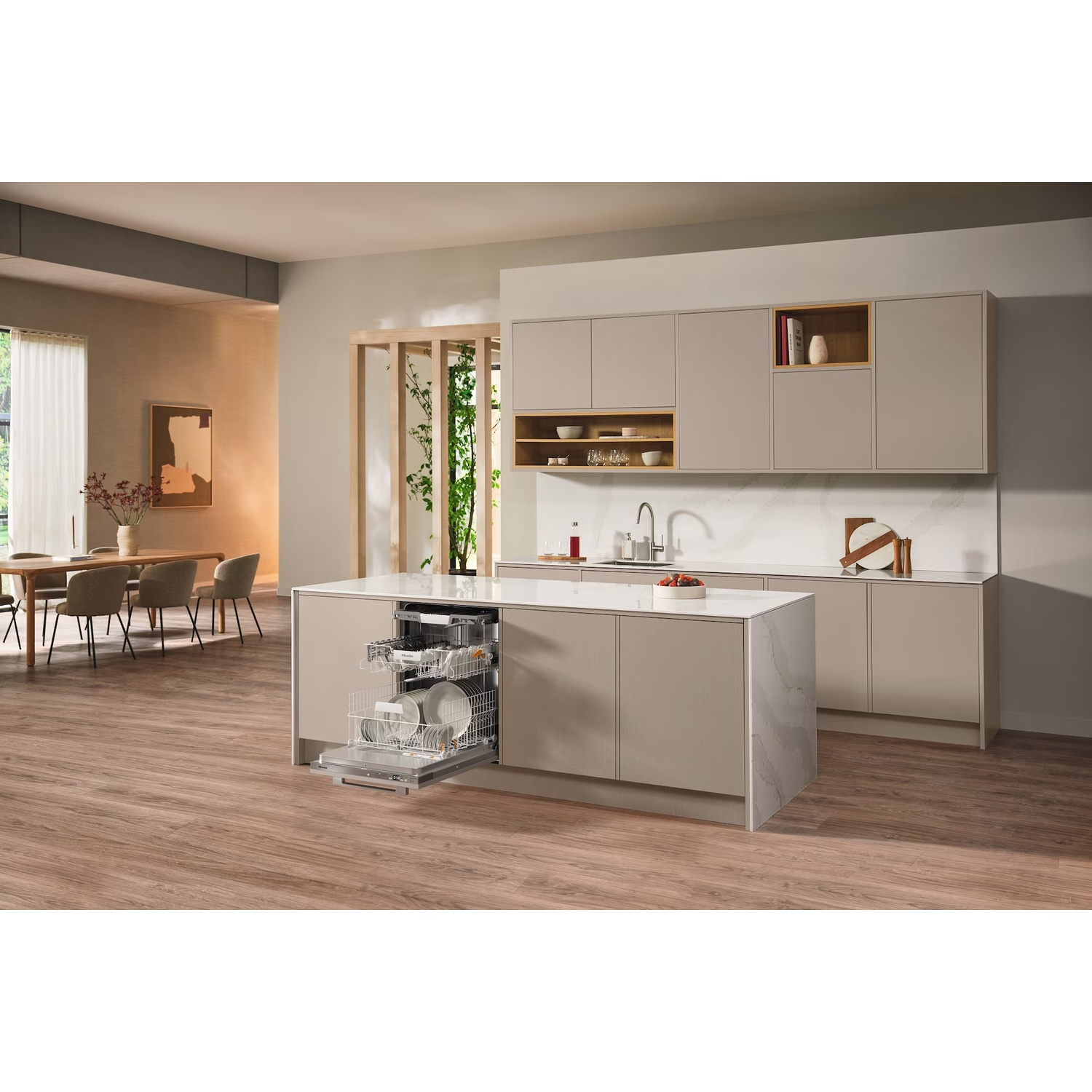 Een moderne keuken met een open vaatwasser, vol borden. Een kookeiland in het midden met kasten.