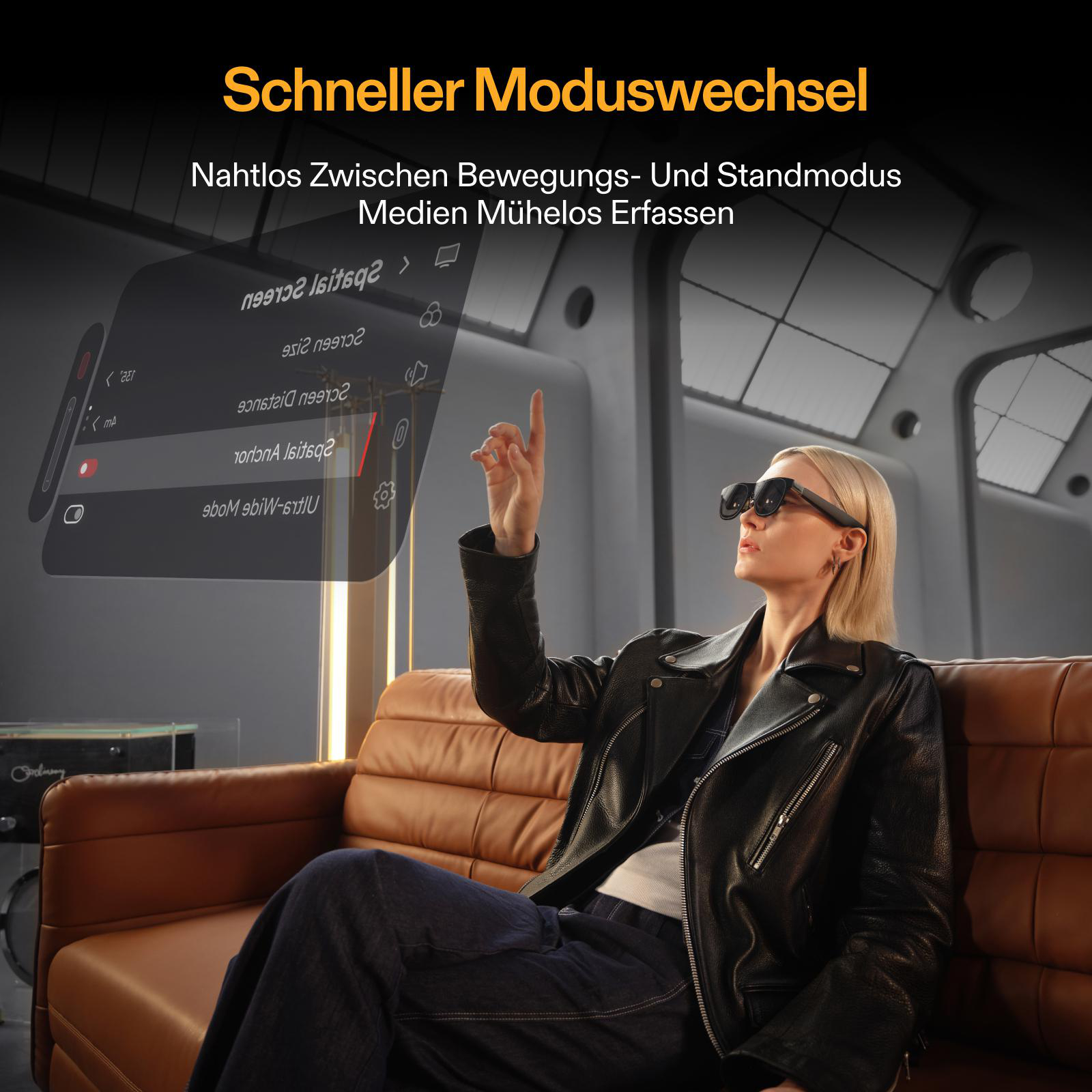 Eine Frau mit Brille interagiert mit einem transparenten Bildschirm. Sie sitzt auf einem braunen Sofa und trägt eine schwarze Jacke.
