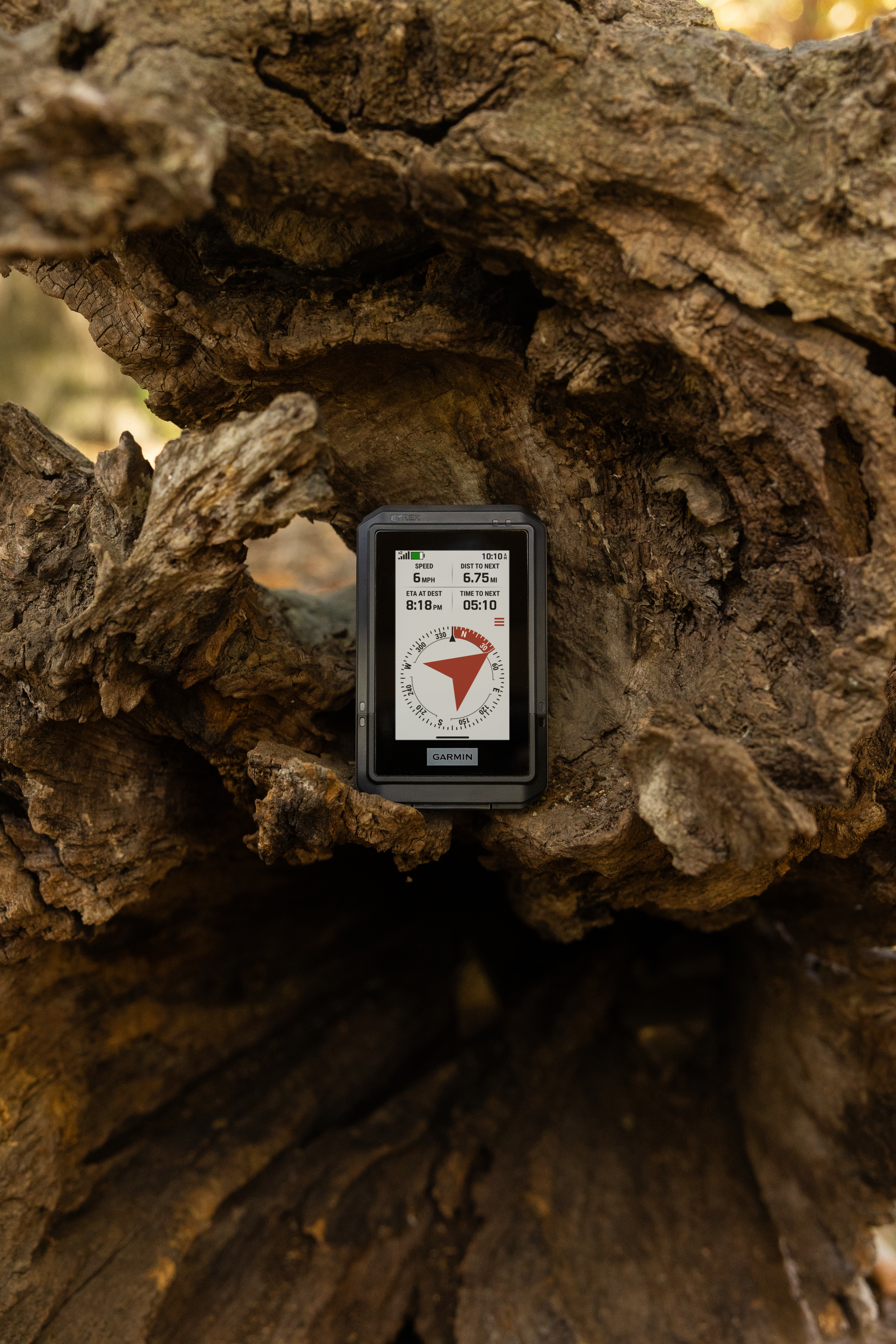 Ein Garmin GPS-Gerät zeigt Geschwindigkeit, ETA und Entfernung an. Es liegt auf strukturiertem, braunem Holz.