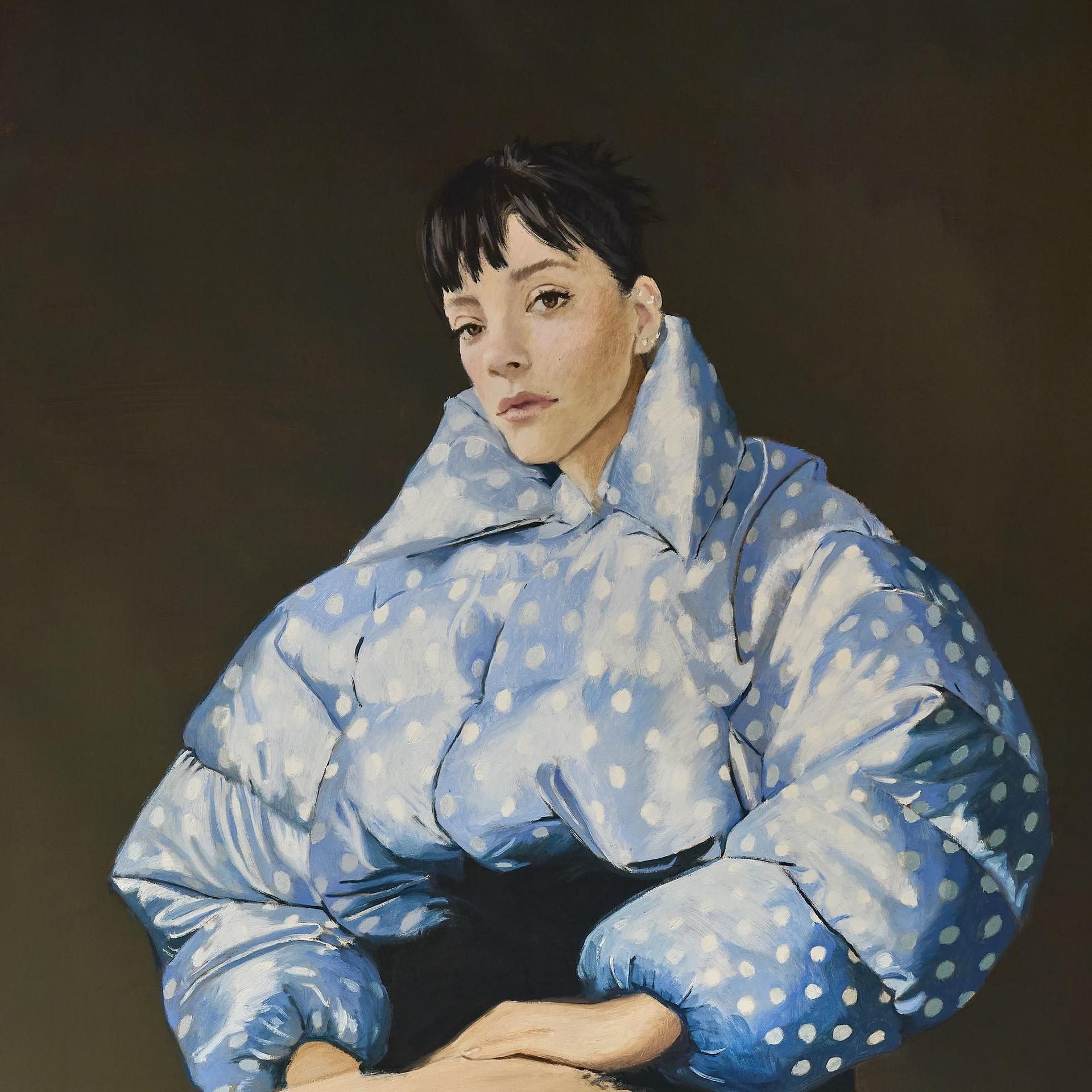Une femme en veste bleue à pois sur fond sombre, regardant vers l'avant. Ses cheveux sont courts et noirs.