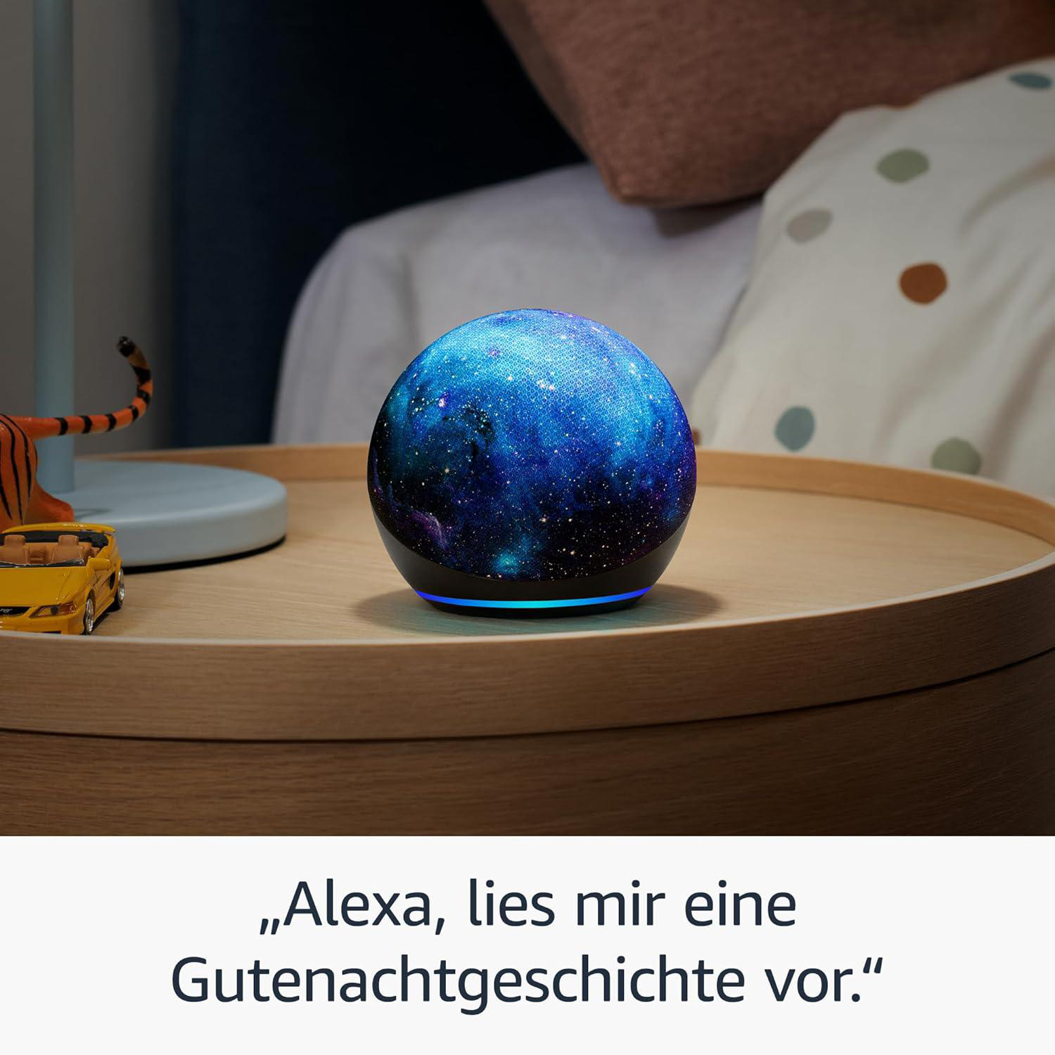 Ein Smart Speaker mit Sternenhimmel-Display steht auf einem Nachttisch. Ein gelbes Spielzeugauto und ein Tigerspielzeug liegen daneben.
