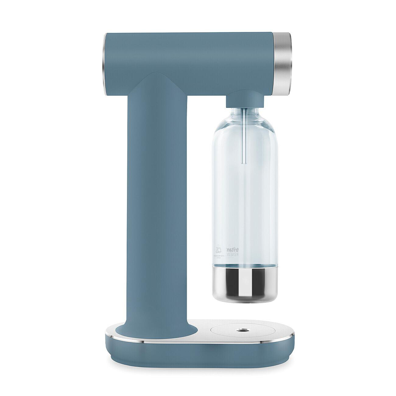 Ein blau-silberner Sodabereiter. Er hat eine klare Flasche und einen silbernen Sockel. Das Design ist modern und elegant.