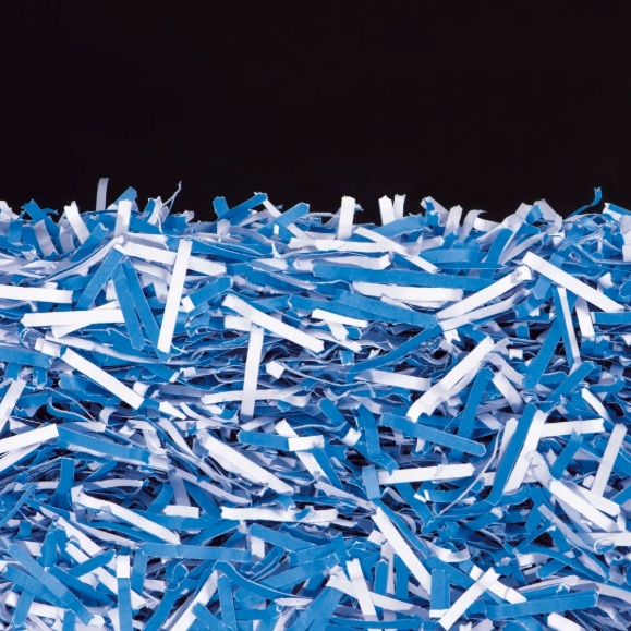 Pocięty niebieski i biały papier na czarnym tle. Kawałki papieru są rozrzucone, wypełniając dolną część obrazu.