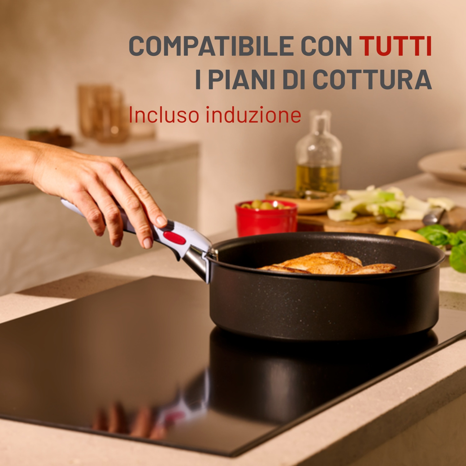 Una mano tiene il manico di una padella sopra un piano cottura nero. Una padella con cibo è sul fornello. Testo in italiano.