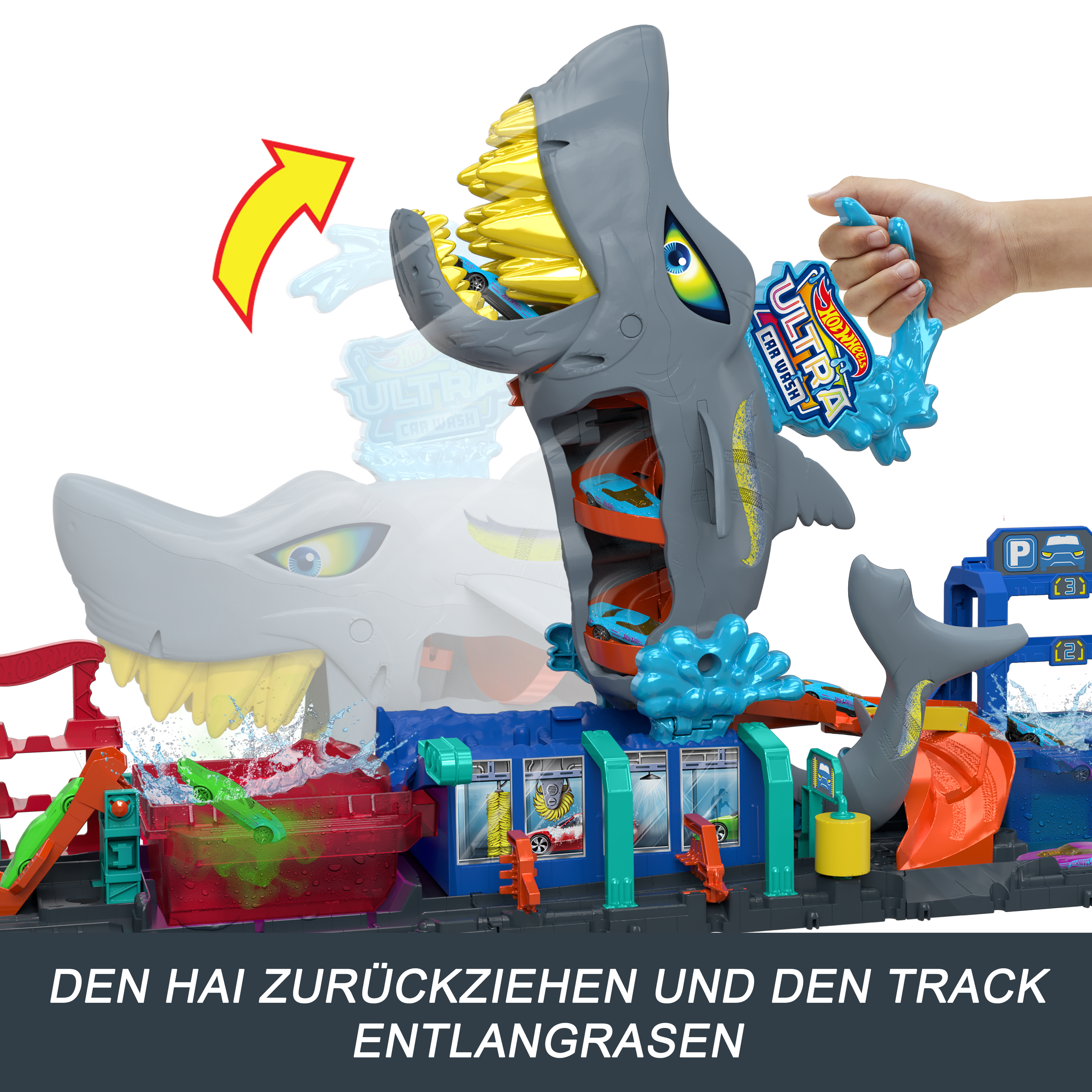 Ein haiförmiges Autowaschspielzeug. Eine Hand hält eine blaue Wasserspritze. Autos fahren durch den Mund des Hais und die Strecke.