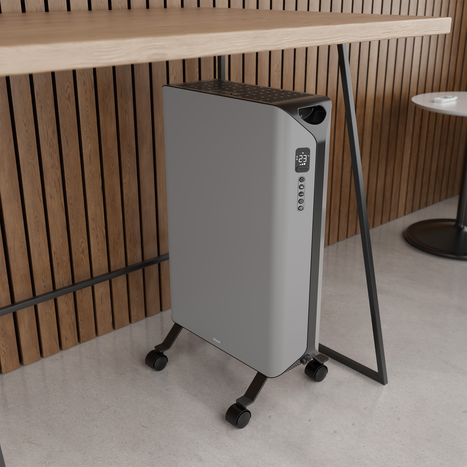 Een grijze elektrische kachel op wielen staat onder een houten tafel. Een kleine tafel staat op de achtergrond. De muur is van houten planken.