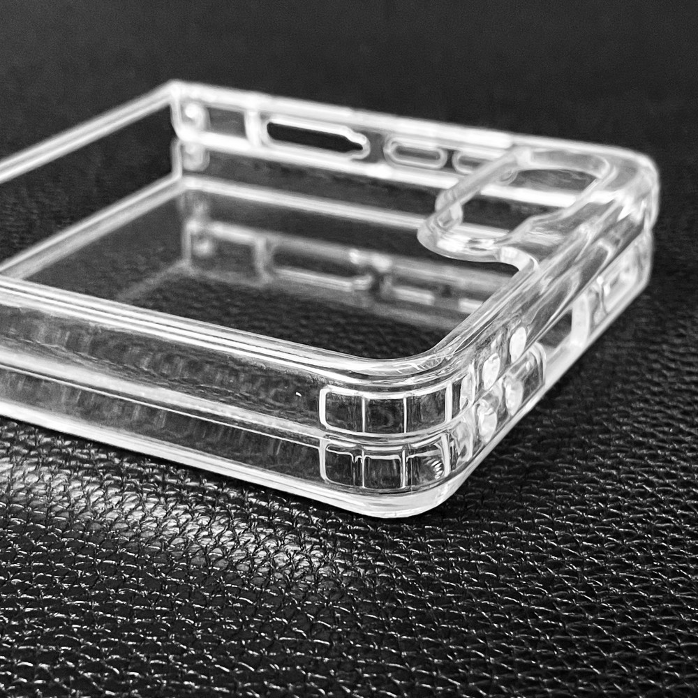 Átlátszó telefontok texturált fekete felületen. A tok szögben van, átlátszó szerkezetét mutatja.