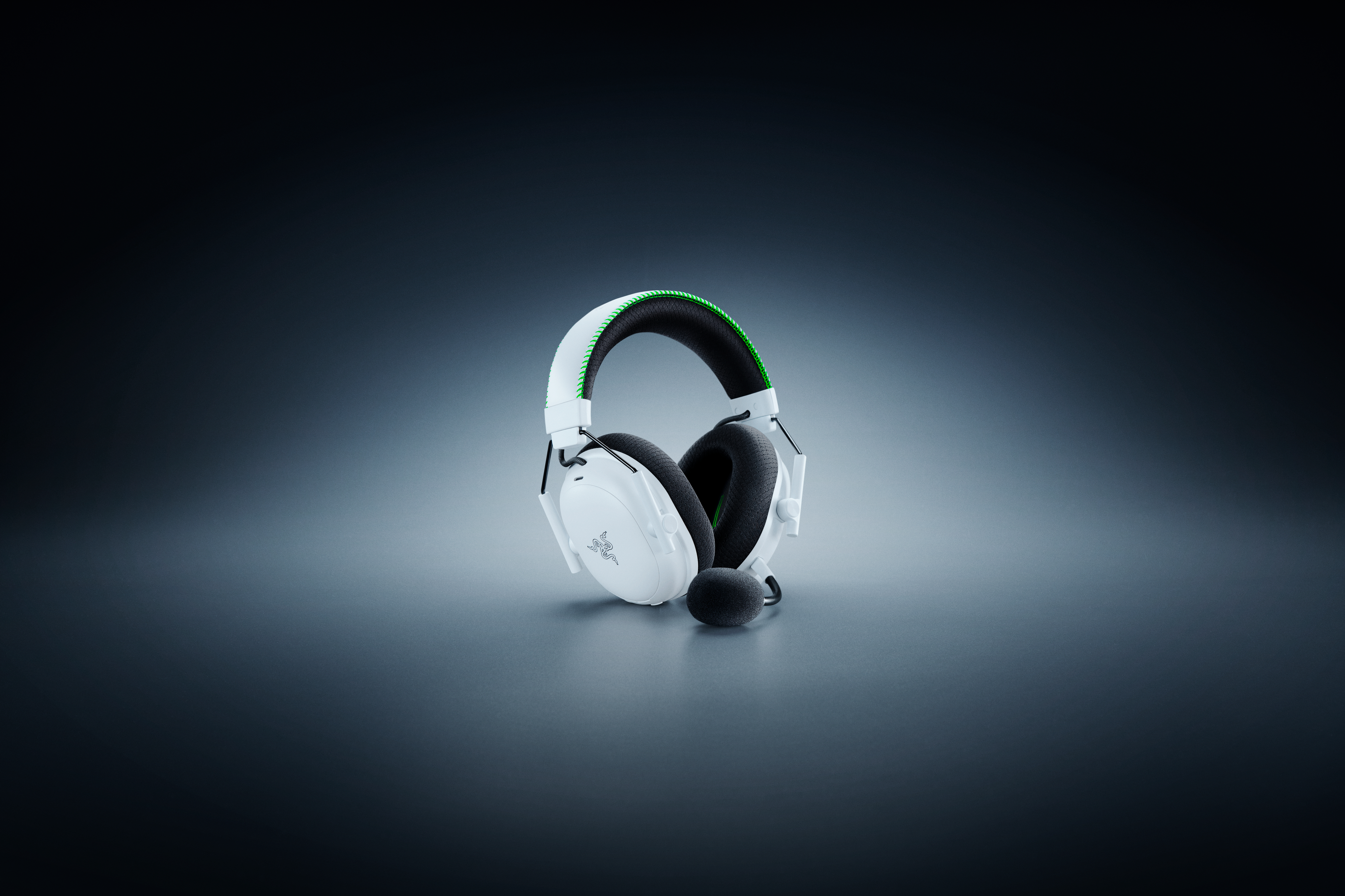 Weißes Gaming-Headset mit grünen Akzenten und Mikrofon auf grauem Farbverlauf.