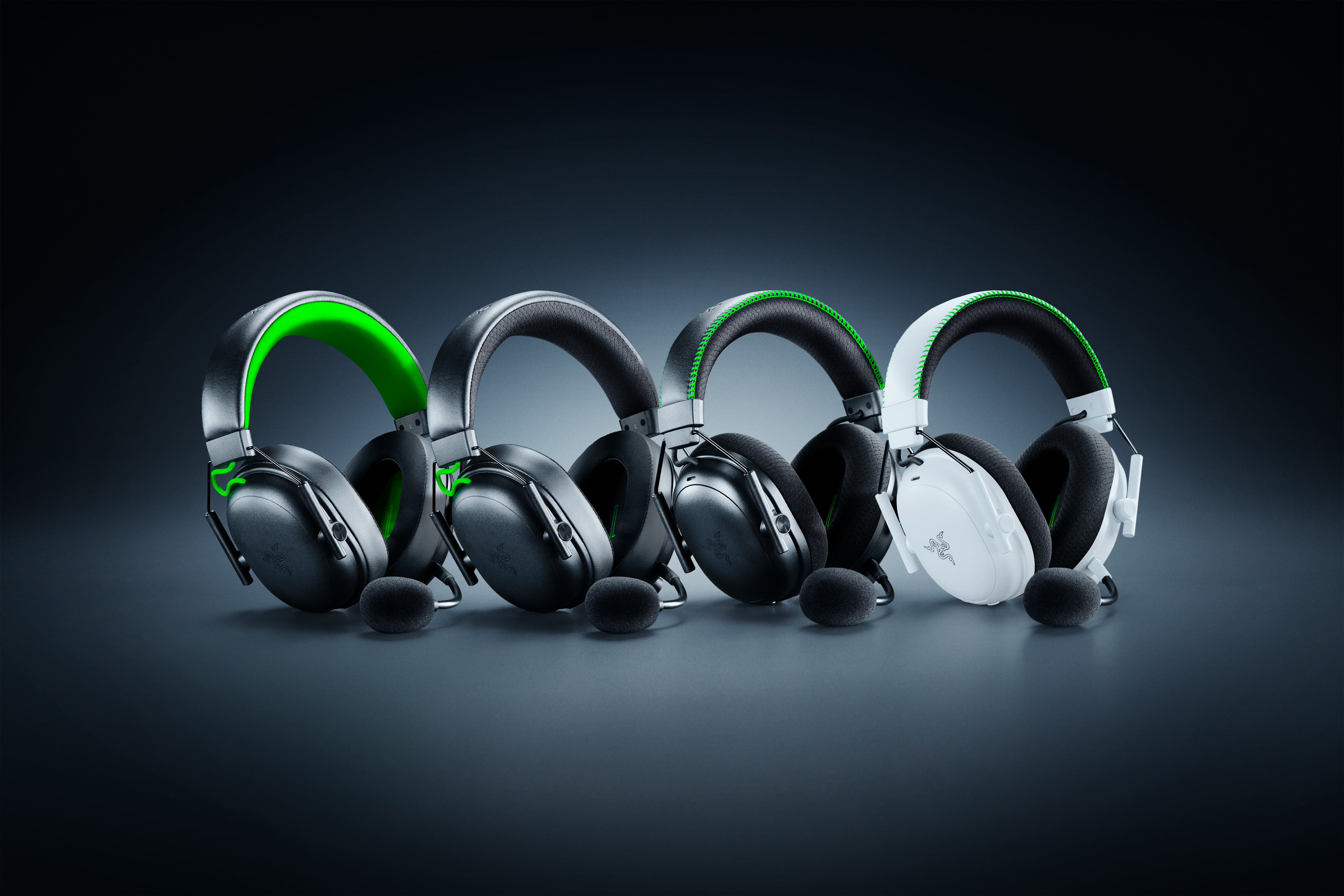 Vier Razer-Gaming-Headsets in einer Reihe. Sie sind schwarz und weiß, mit grünen Akzenten. Jedes hat ein Mikrofon.