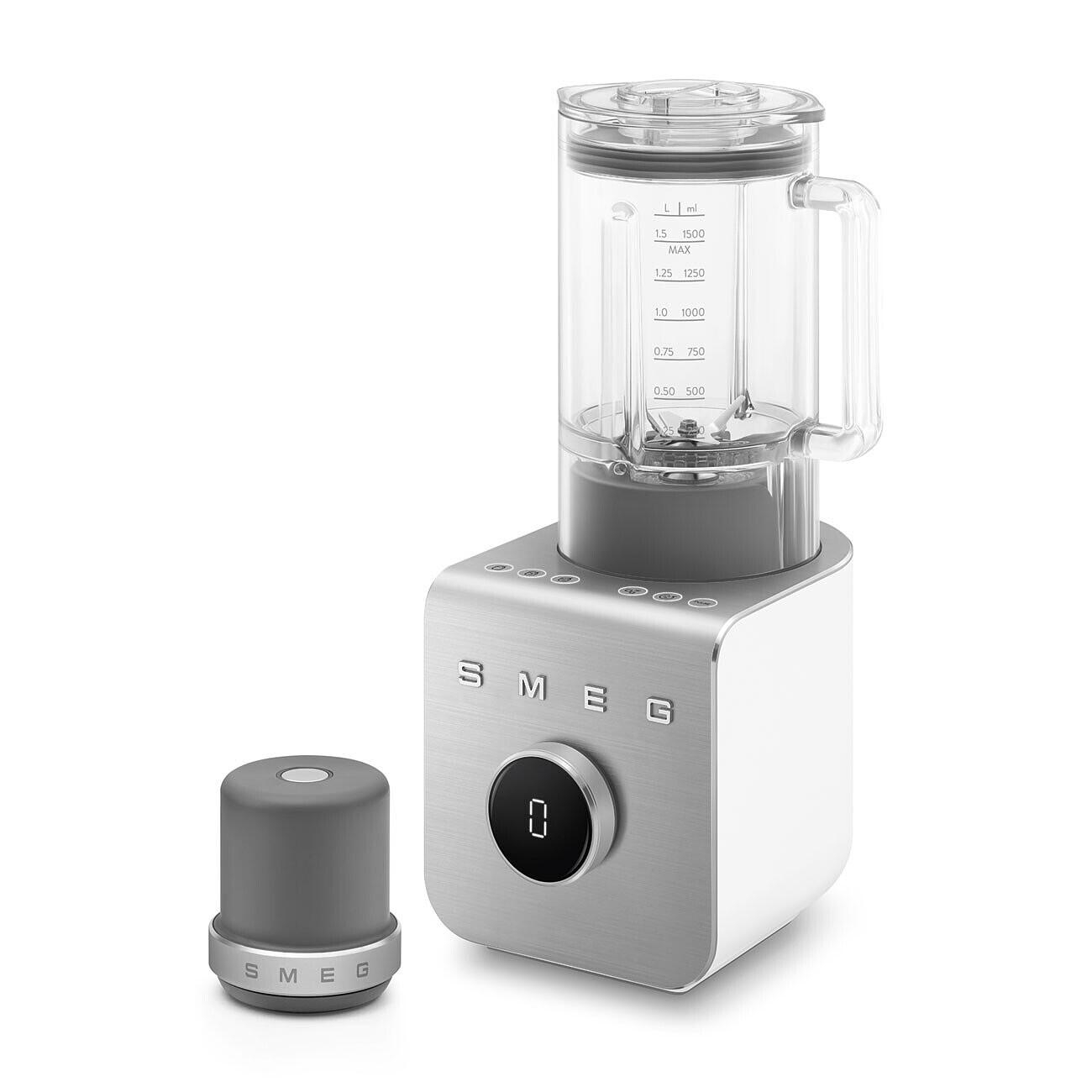 Ein weißer und silberner SMEG-Mixer mit abnehmbarem grauen Sockel und separatem grauen Deckel. Der Mixer hat einen durchsichtigen Behälter.