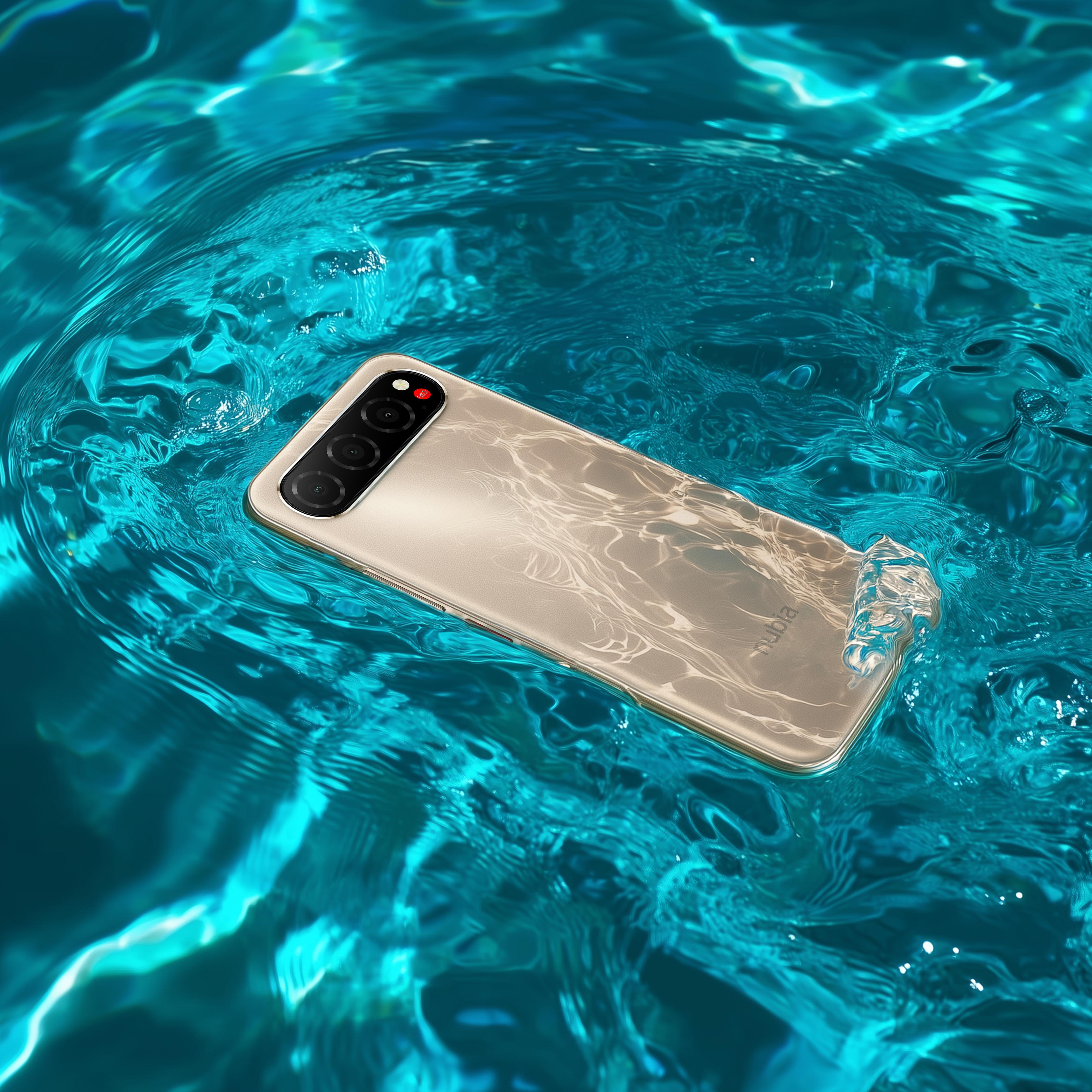 Ein goldenes Telefon schwimmt in türkisfarbenem Wasser. Die Kameralinsen des Telefons sind sichtbar. Wasser spritzt herum.