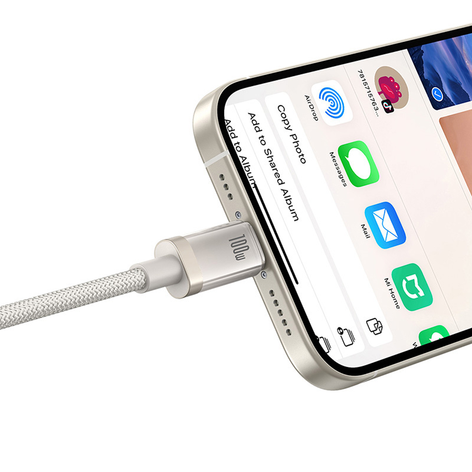 Un teléfono se está cargando con un cable. La pantalla muestra iconos de aplicaciones. Primer plano del teléfono y el cable.